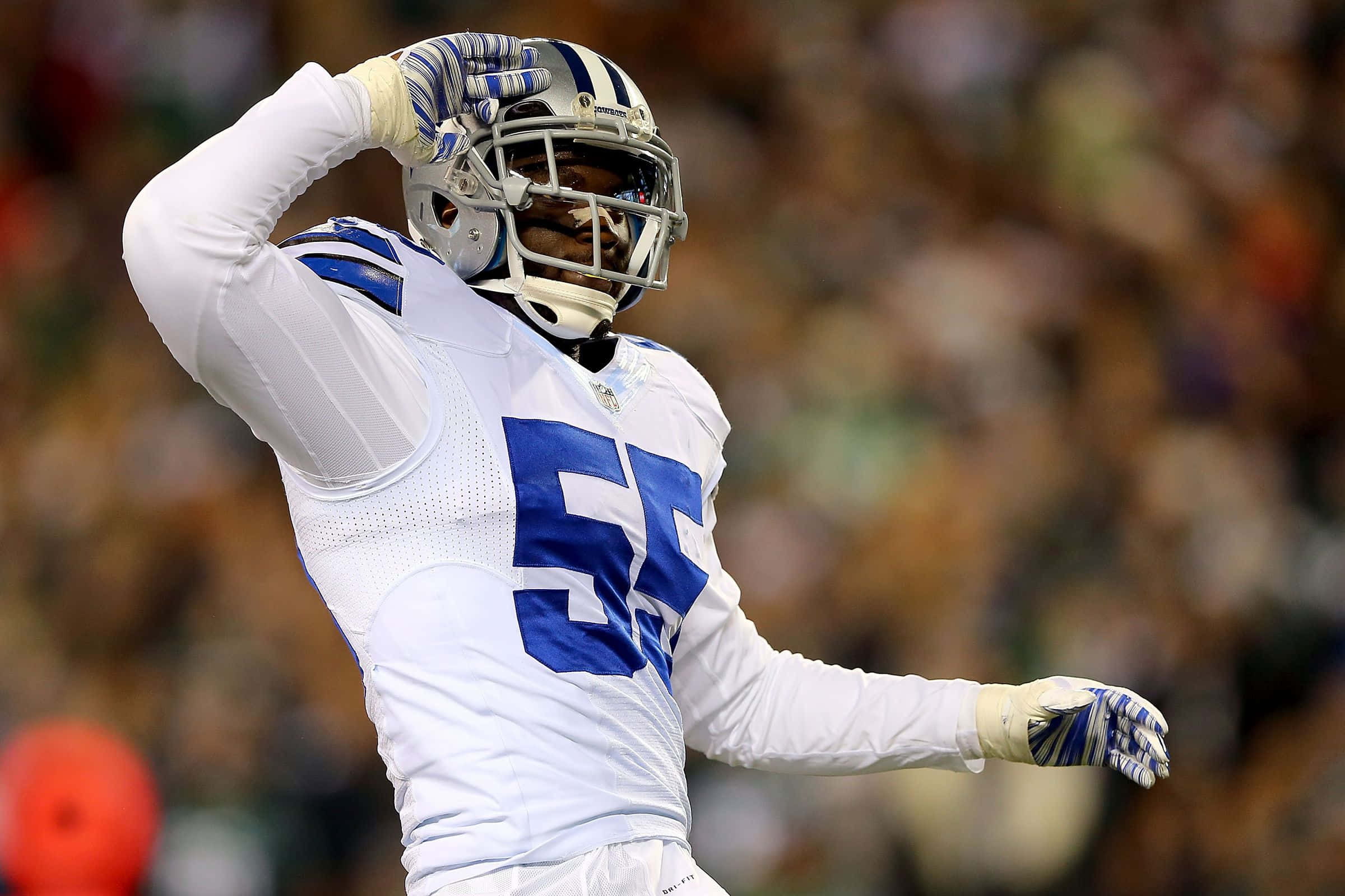 Dallas Cowboys Players 桌布 壁紙 — 一名身穿白色和藍色球衣的達拉斯牛仔隊美式足球員在夜間比賽中舉手慶祝。