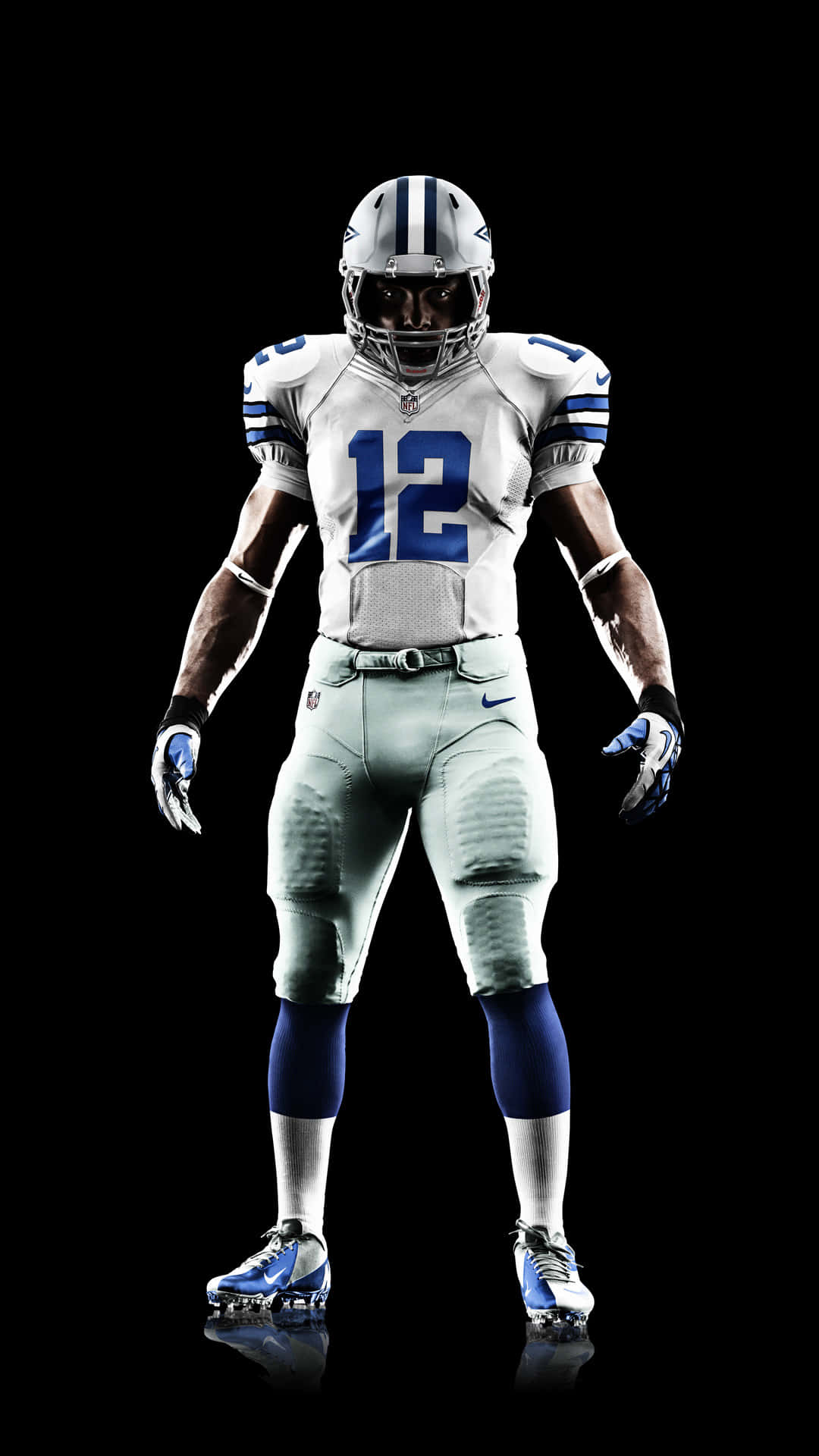 Dallas Cowboys Players 桌布 壁紙 — 一名身穿白色和藍色球衣的達拉斯牛仔隊美式足球員，自信地站在黑色背景前，穿著反光鞋。