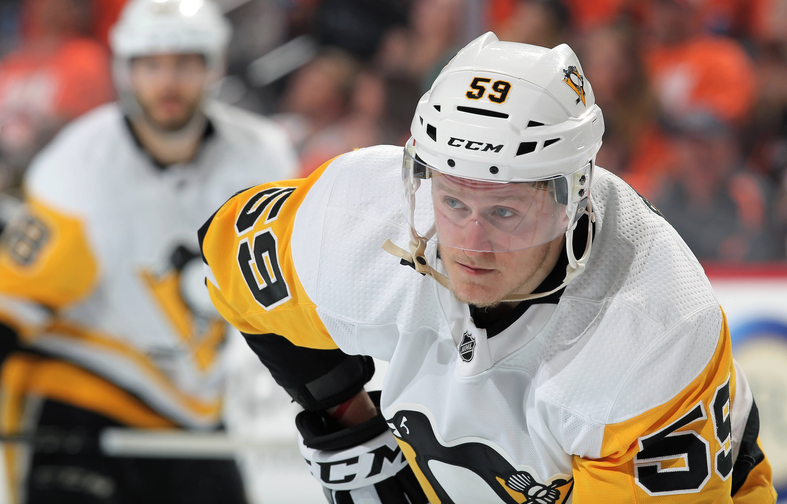 hockey 桌布 壁紙 — 一名身穿白色和金色球衣、號碼59的專注曲棍球運動員在比賽中在冰上向前傾身。