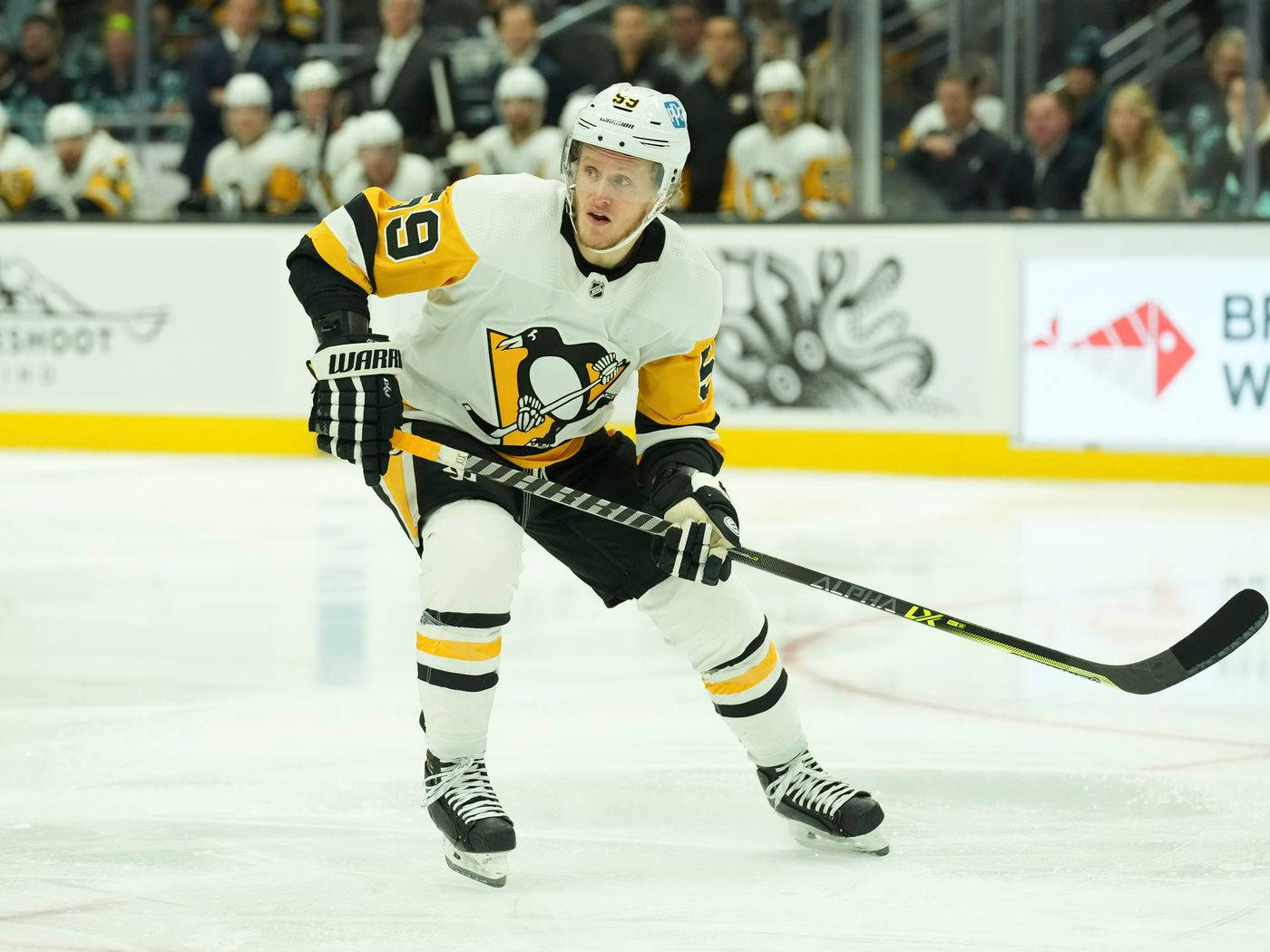 hockey 桌布 壁紙 — 一名身穿白色和金色球衣的冰球運動員在比賽中拿著球棍在冰上激烈滑行。