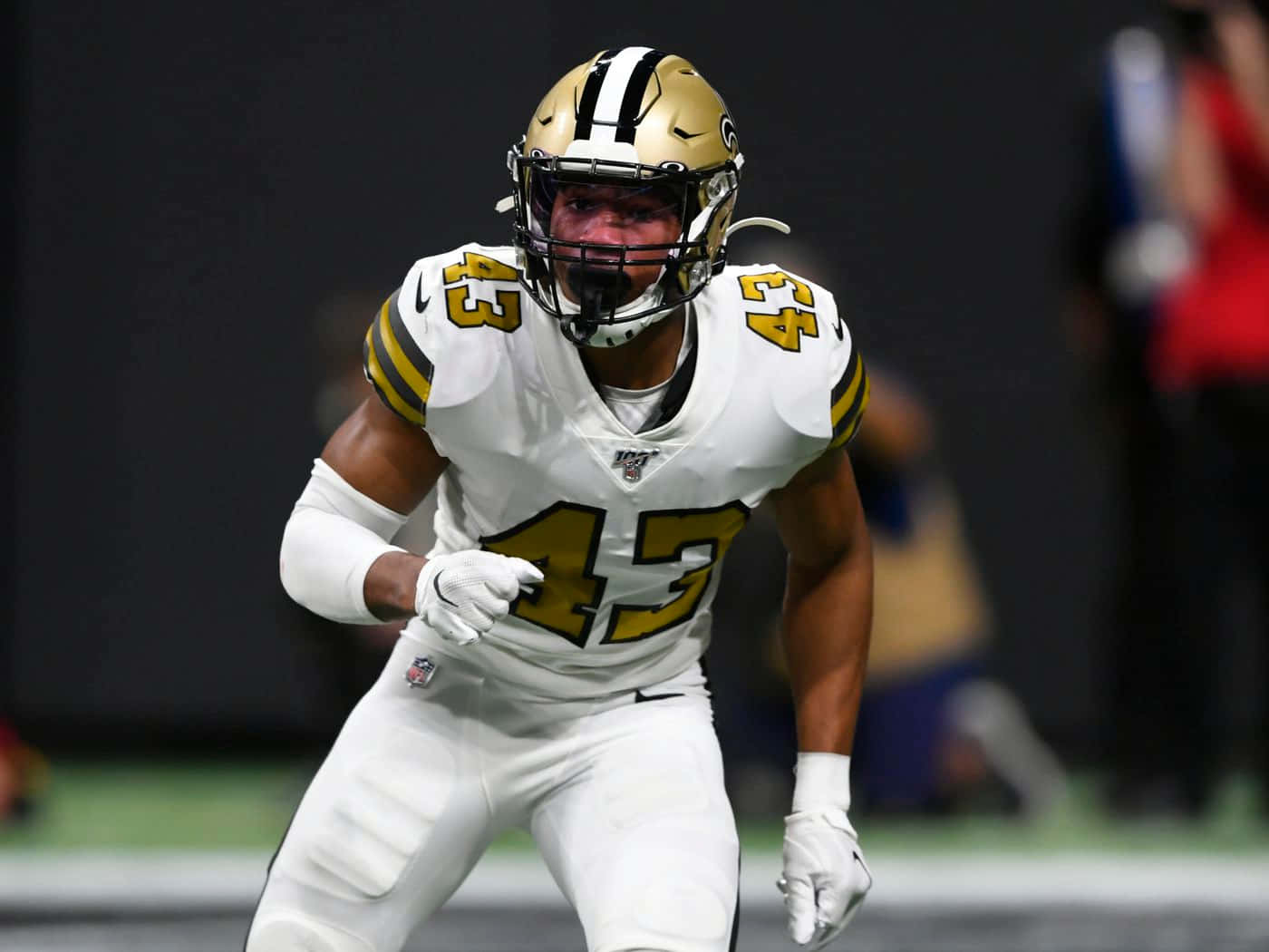Marcus Williams 桌布 壁紙 — 一名身穿白色和金色球衣的足球運動員在昏暗的球場上專注地全力衝刺。