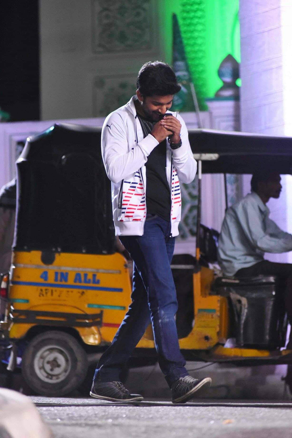 Indian 桌布 壁紙 — 一名身穿白色外套的男子在夜晚行走於一輛黃色自動三輪車旁，背景是綠色燈光下的清真寺建築。