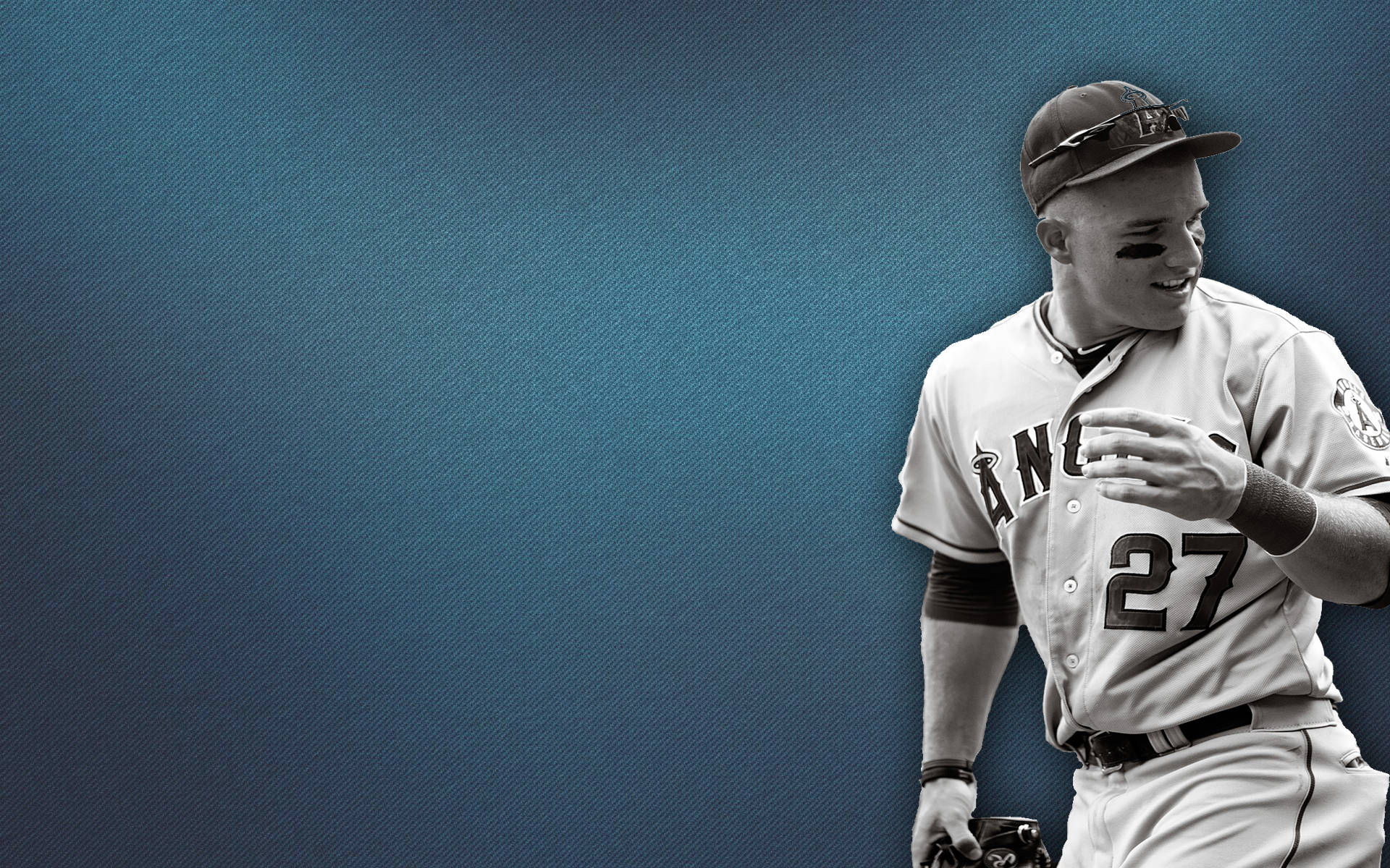 Mike Trout 桌布 壁紙 — 一名身穿白色天使隊球衣、背號27的棒球運動員，在帶有紋理的藍色背景前微笑著手持球棒。