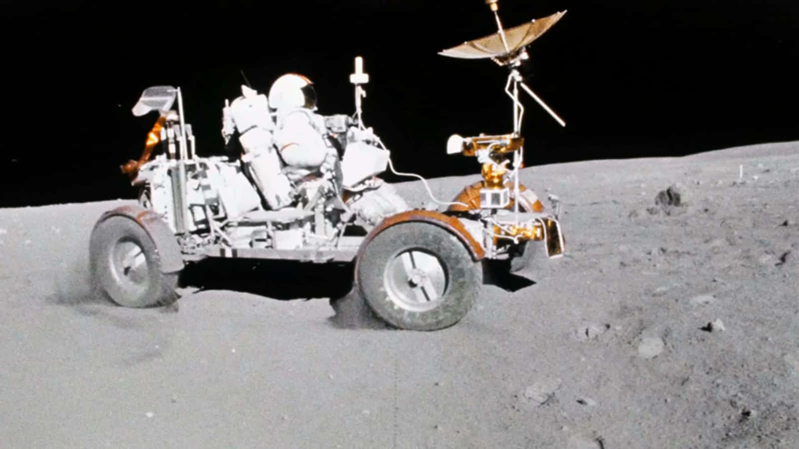Moon Landing 桌布 壁紙 — 一名身穿白色太空衣的太空人在黑色天空下駕駛月球車穿越灰色月球表面。