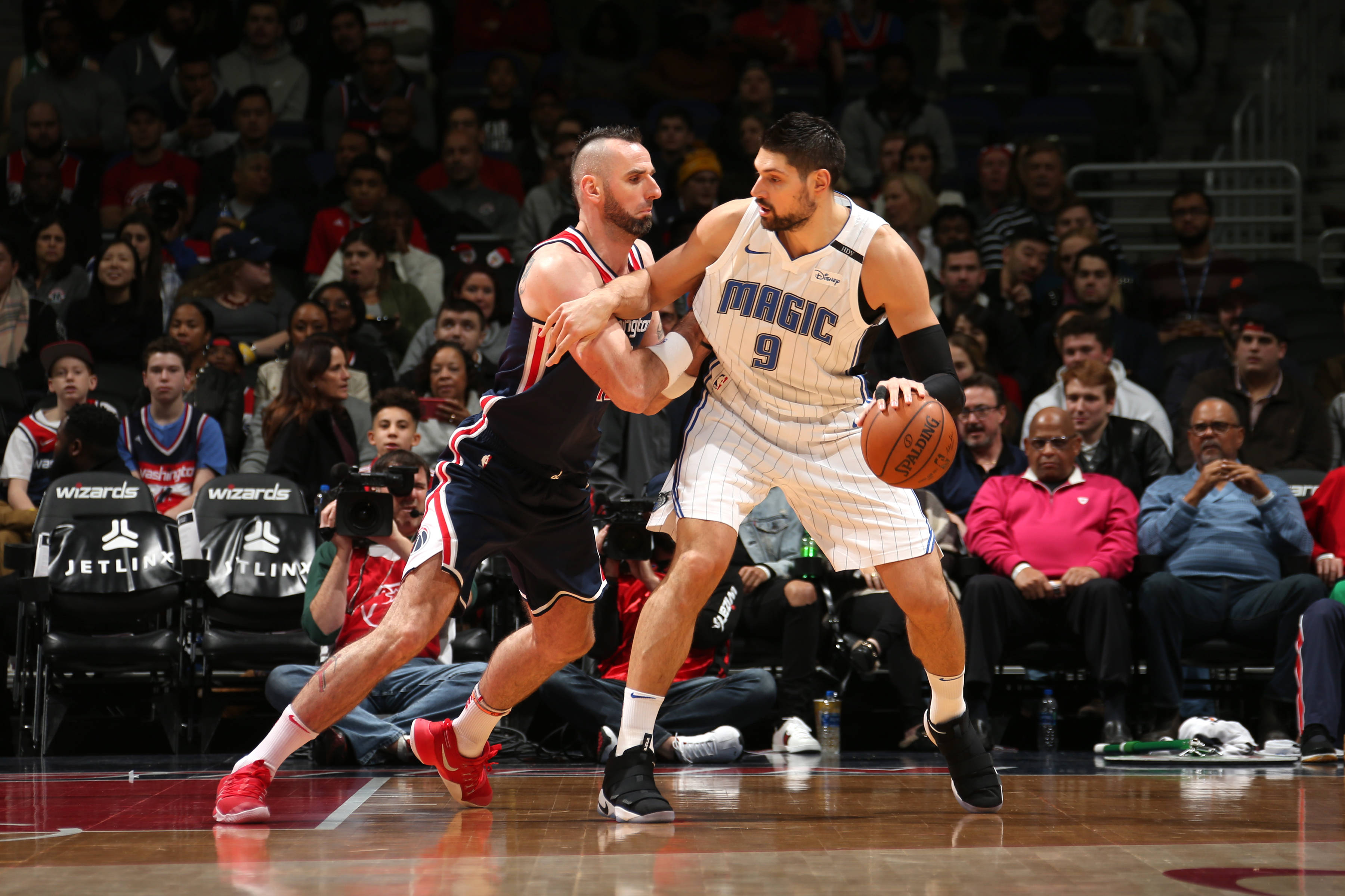 NBA 桌布 壁紙 — 一名身穿白色奧蘭多魔術隊球衣的籃球運動員在激烈的比賽中運球，同時被一名身穿黑色球衣的對手緊密防守。