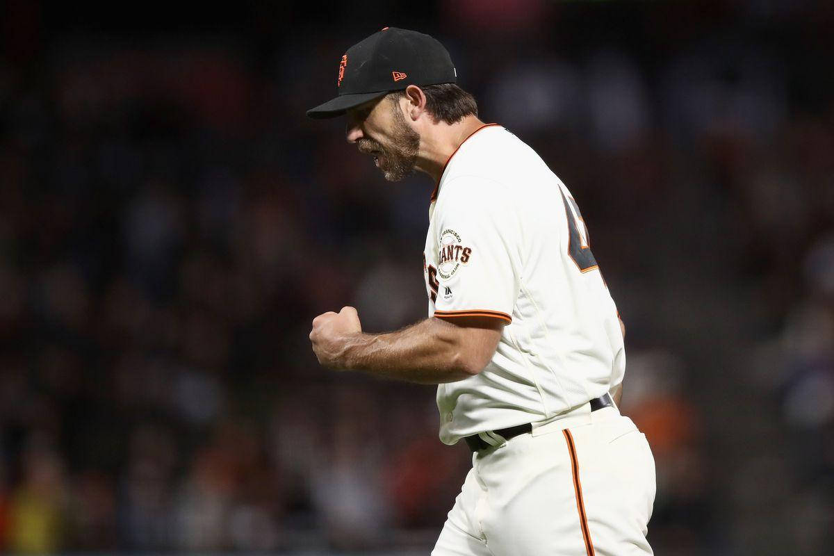 madison bumgarner 桌布 壁紙 — 一名身穿白色巨人隊球衣的棒球投手在球場燈光下握緊拳頭慶祝勝利。