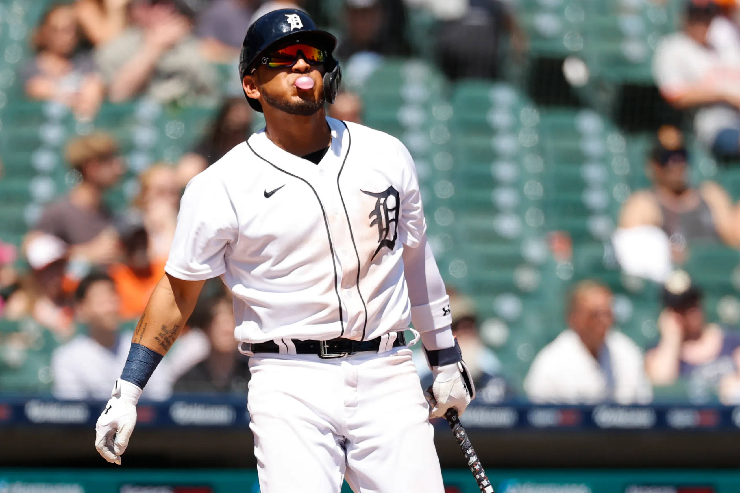 tigers 桌布 壁紙 — 一名身穿白色底特律老虎隊球衣的棒球選手，在陽光明媚的球場上拿著球棒吹泡泡糖。