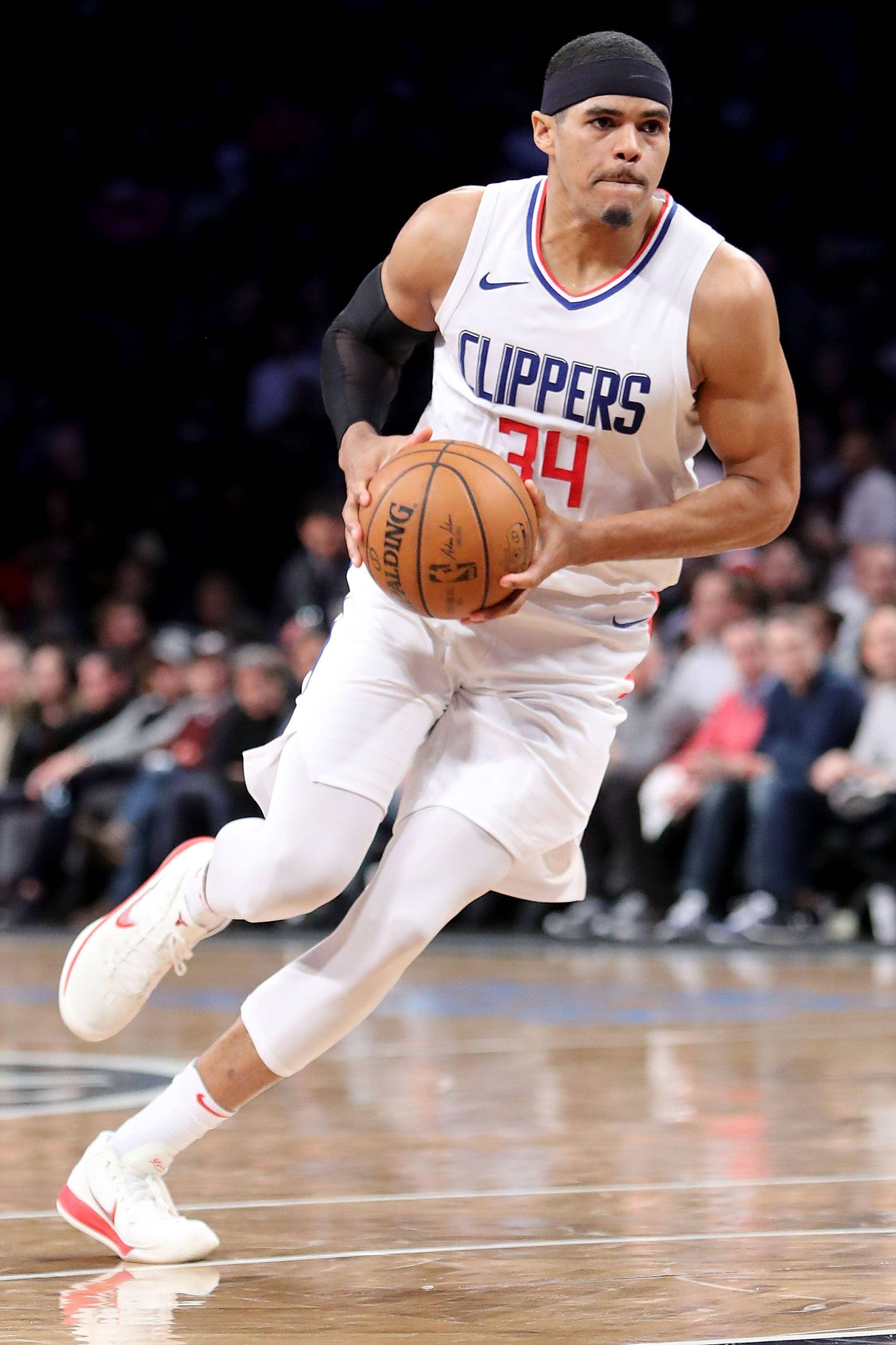 NBA 桌布 壁紙 — 一名身穿白色快艇隊球衣的籃球運動員在明亮的場館燈光下，在比賽中全神貫注地運球。