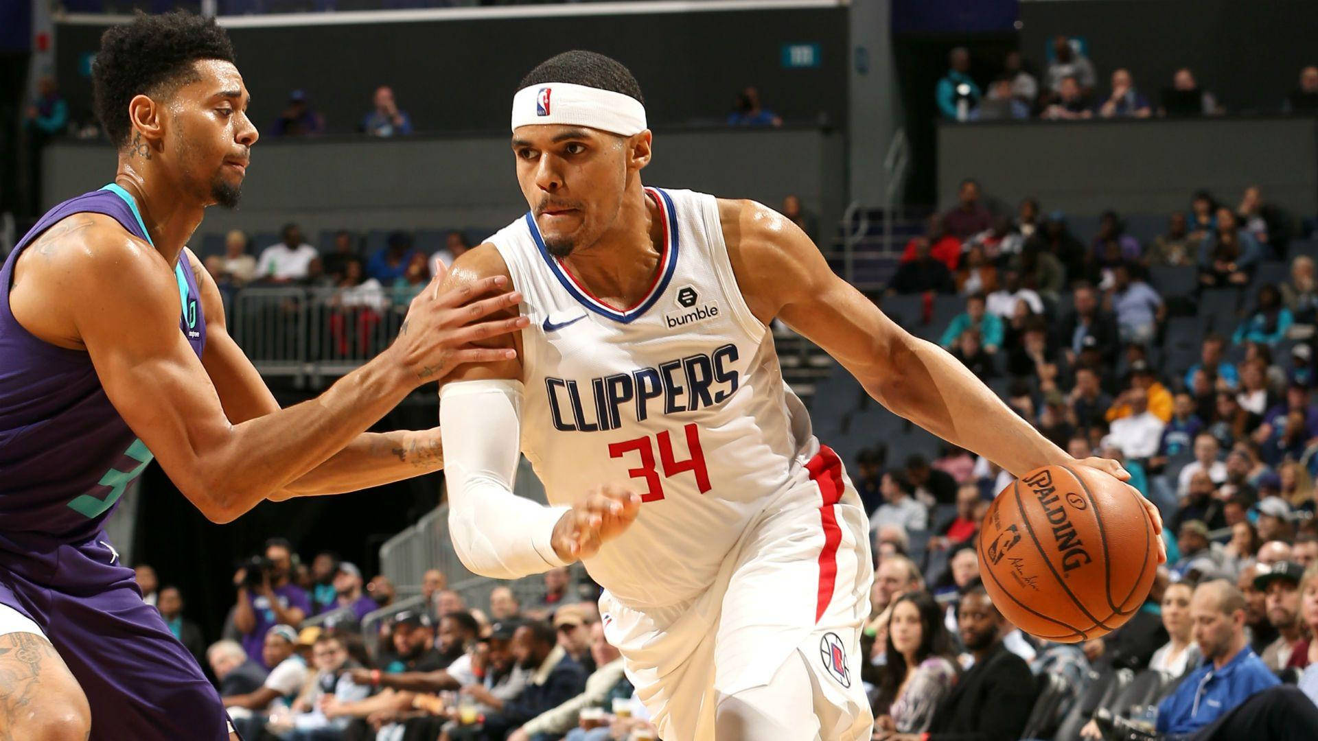 NBA 桌布 壁紙 — 一名身穿白色快艇隊球衣的籃球運動員在比賽中運球，同時被一名身穿紫色球衣的對手緊密防守。