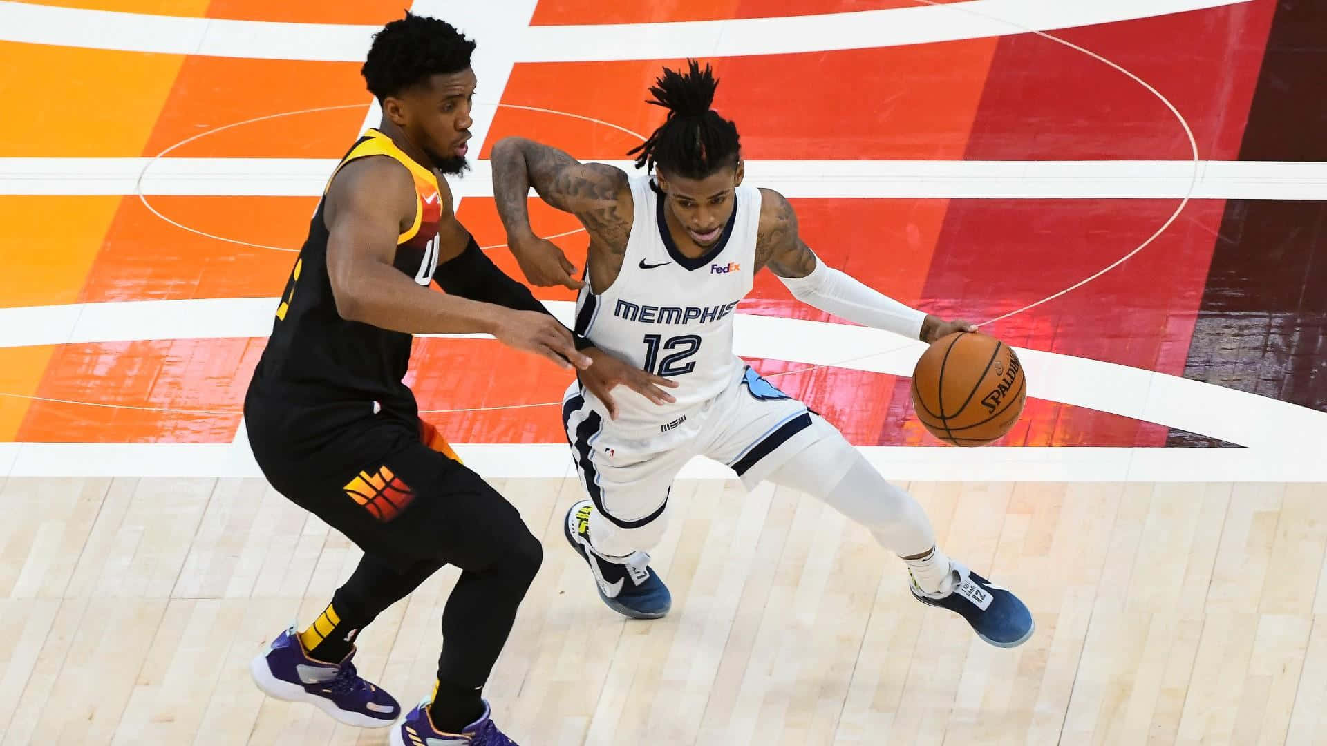 Ja Morant 動圖 桌布 壁紙 — 一名身穿白色曼菲斯球衣的籃球運動員在充滿活力的球場上運球，同時被一名身穿黑黃色球衣的對手緊密防守。