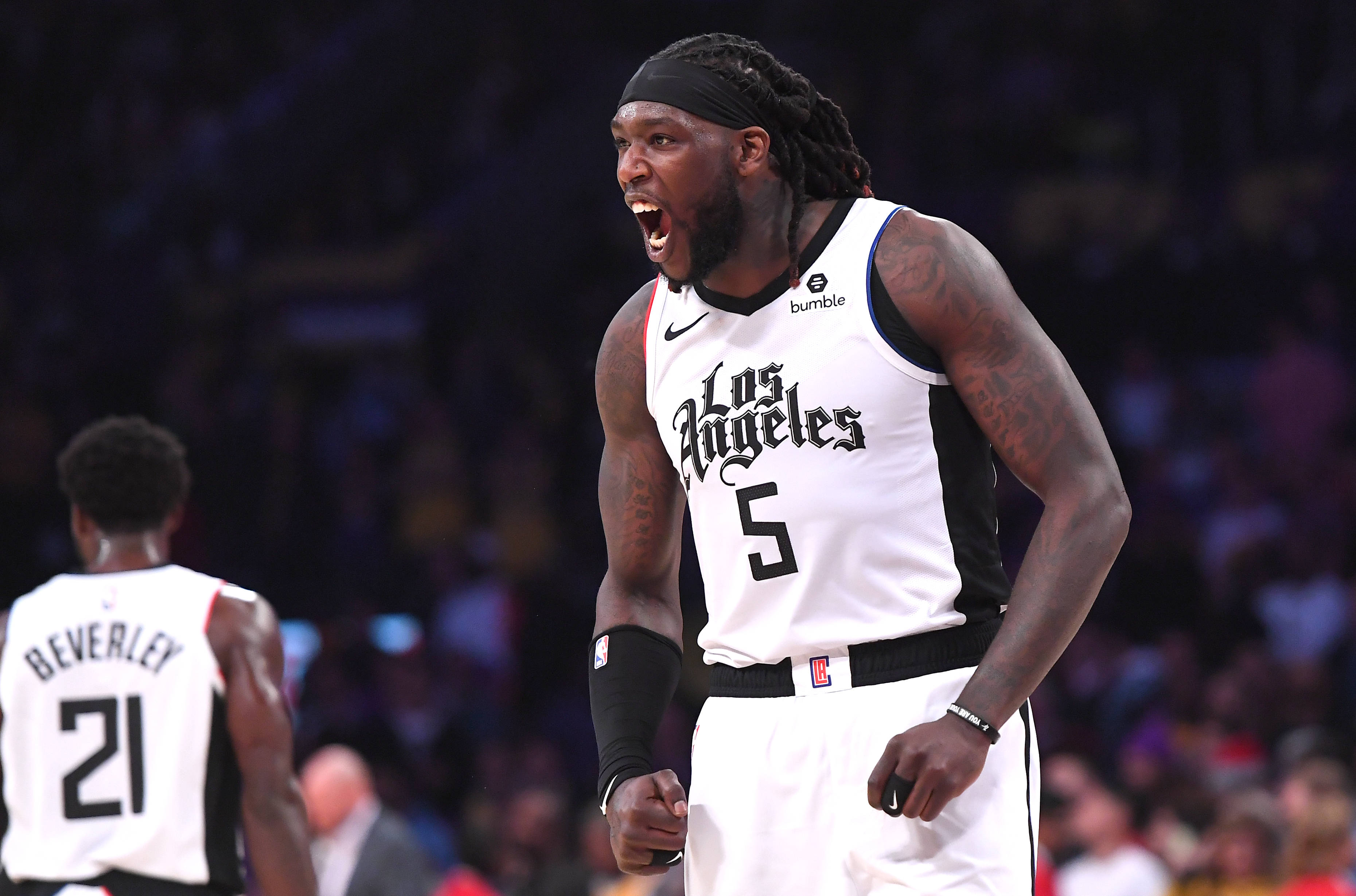 montrezl harrell 桌布 壁紙 — 一名身穿白色洛杉磯球衣的籃球運動員在明亮的場館燈光下，在比賽中激烈咆哮。