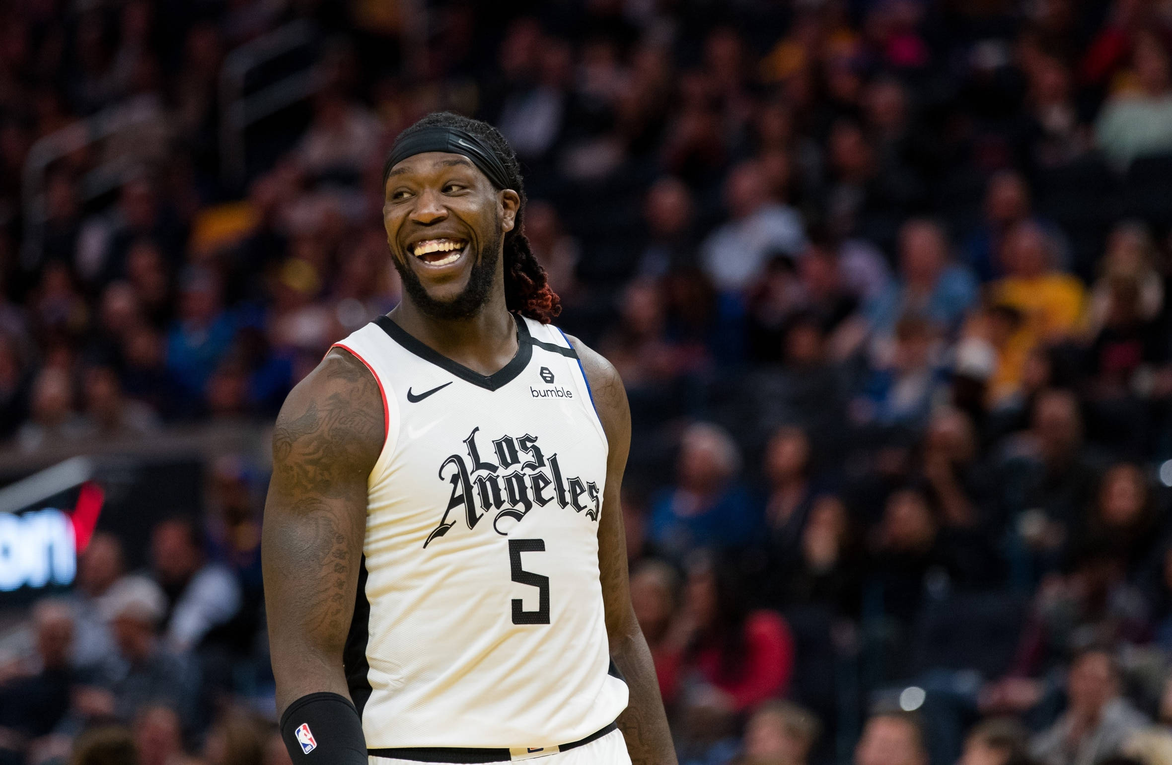 montrezl harrell 桌布 壁紙 — 一名身穿白色洛杉磯球衣的籃球運動員在比賽中大笑，身後是模糊的人群。