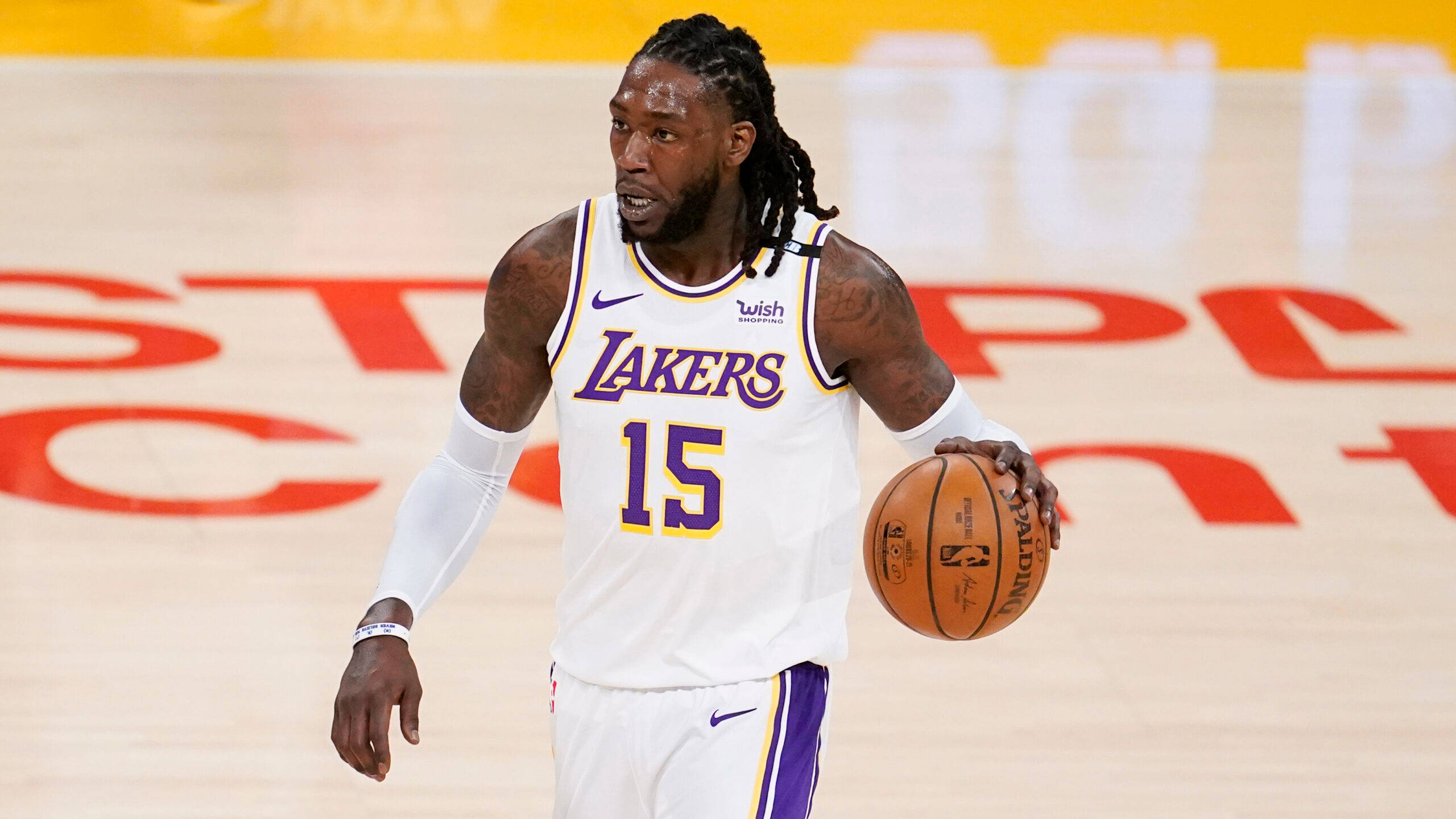 montrezl harrell 桌布 壁紙 — 一名身穿白色湖人隊球衣、背號15的籃球運動員在印有紅色字樣的球場上運球。