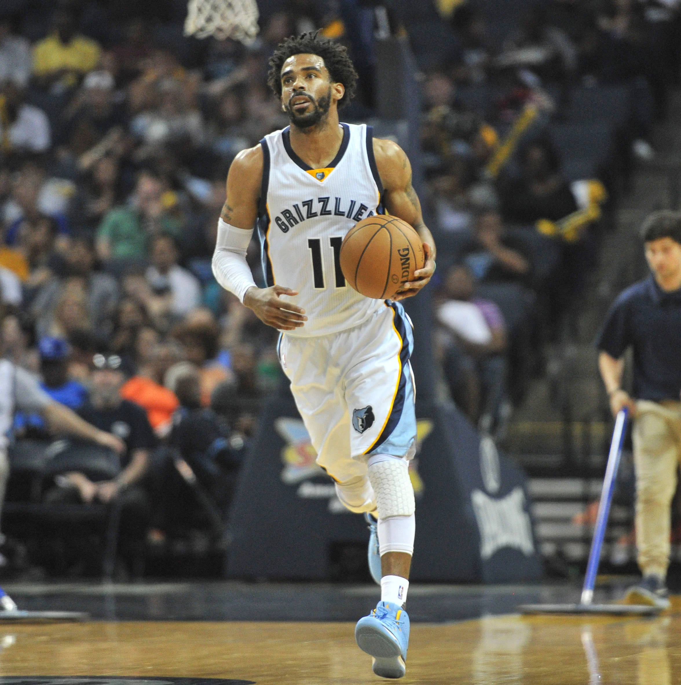mike conley 桌布 壁紙 — 一名身穿白色灰熊隊球衣的籃球運動員在明亮的場館燈光下，於激烈的比賽中運球。