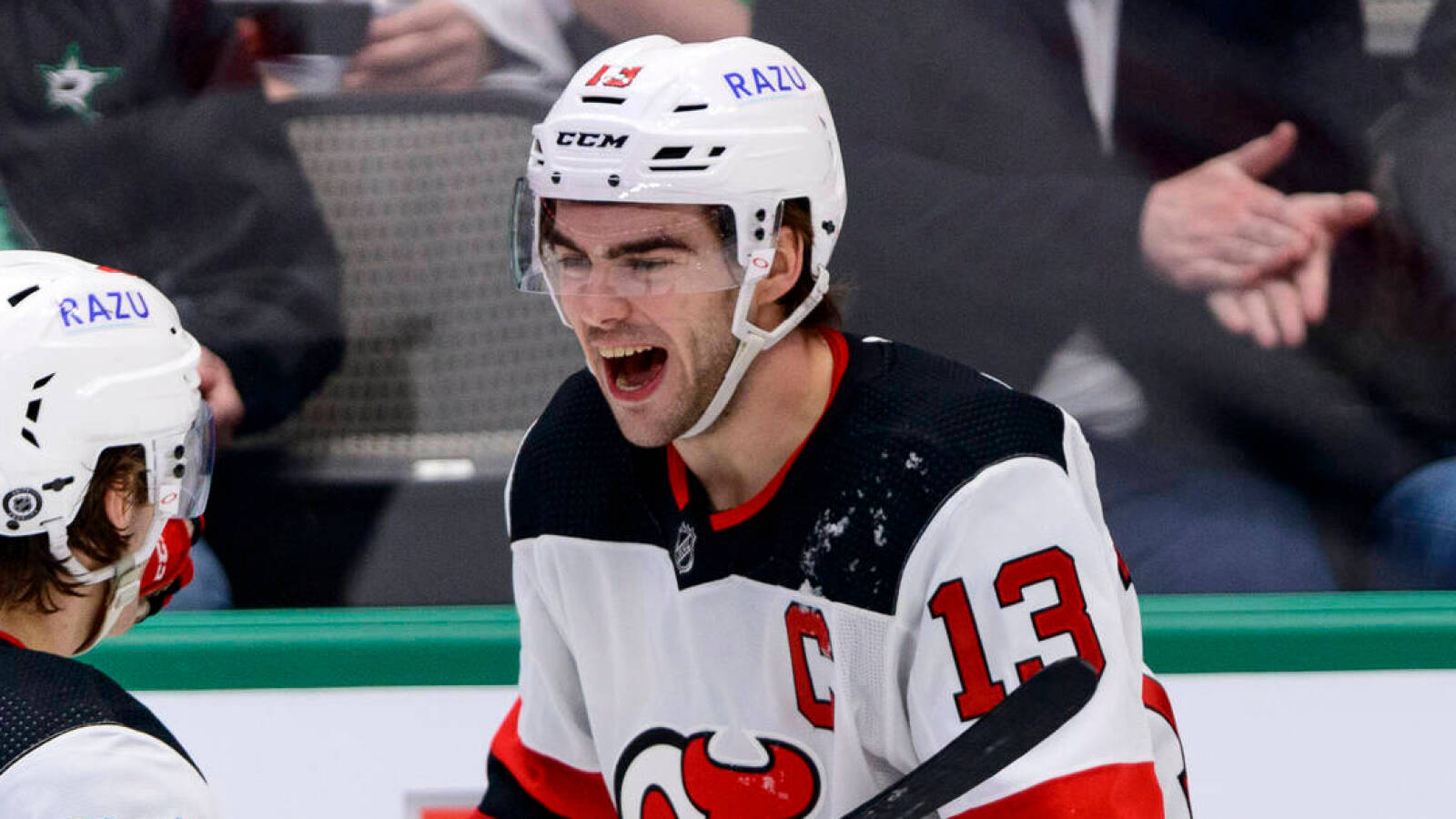 hockey 桌布 壁紙 — 一名身穿白色球衣、帶有紅色點綴和13號的冰球運動員，在比賽中戴著寫有「RAZU」的頭盔，激情地吶喊。