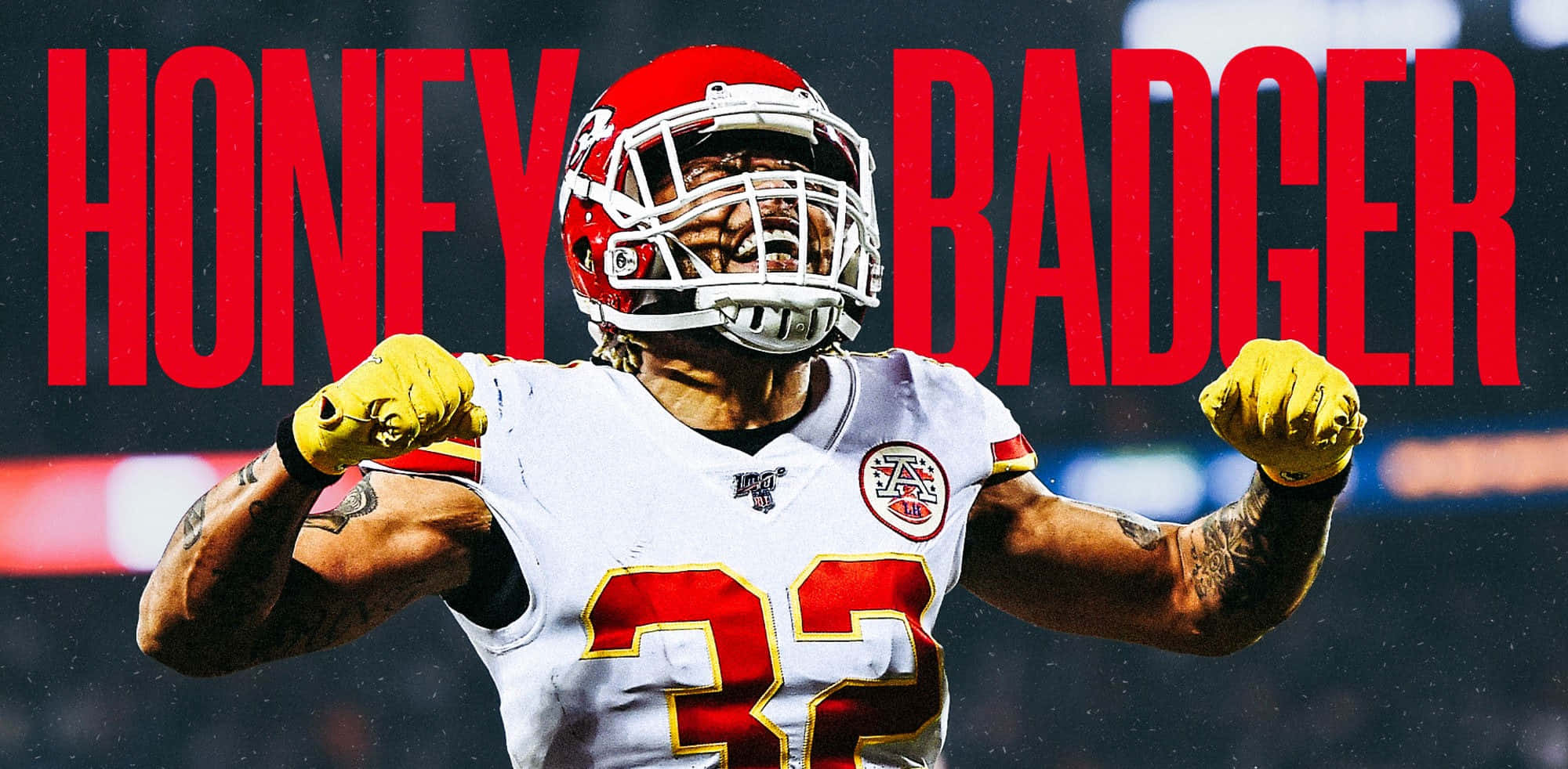 Tyrann Mathieu 桌布 壁紙 — 一名身穿白色球衣、紅色32號碼和紅色頭盔的美式足球員，在粗體紅色「HONEY BADGER」文字下握拳展示肌肉。