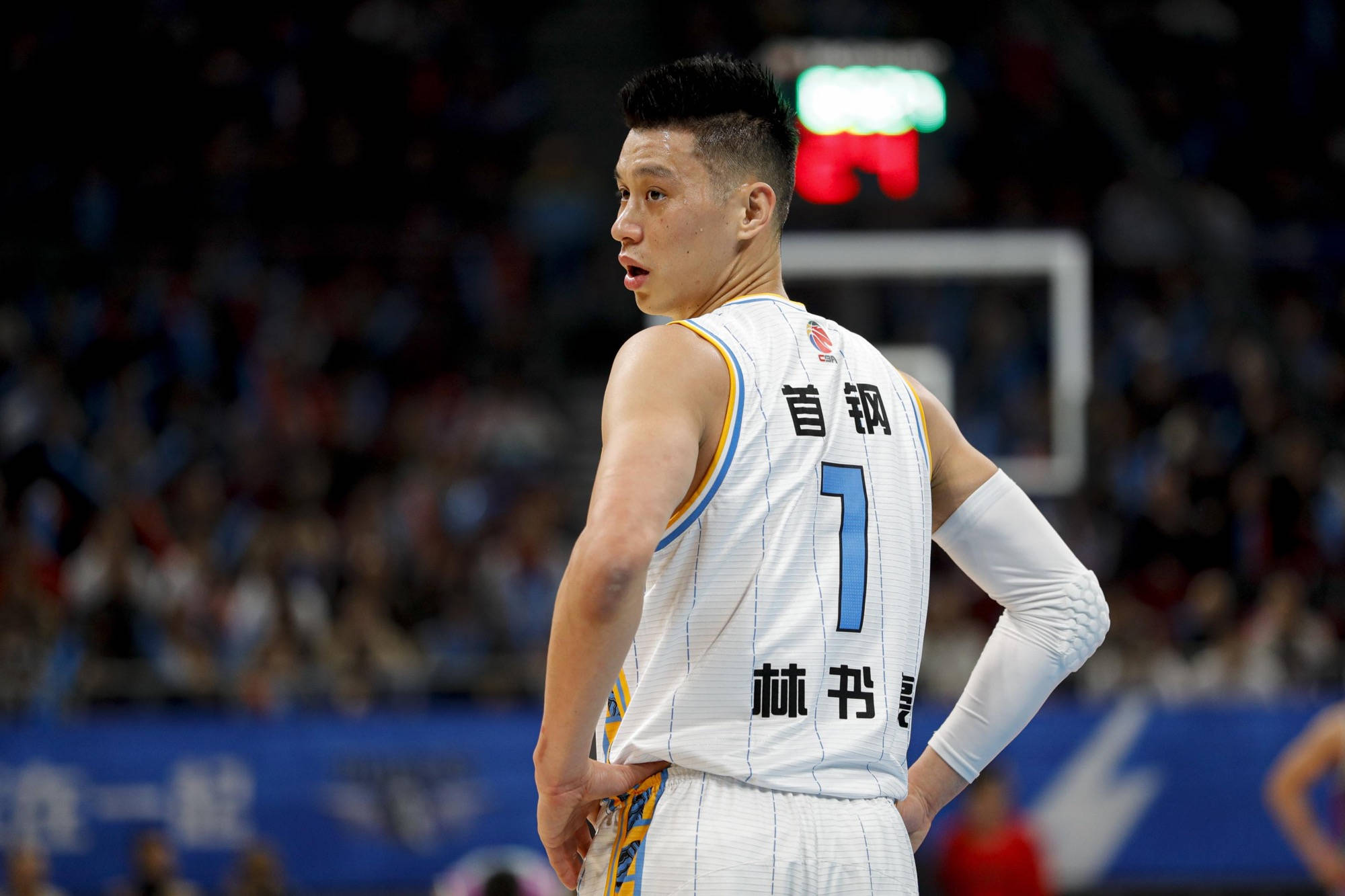 Lin 桌布 壁紙 — 一名身穿白色球衣、背號1號的籃球運動員站在球場上，雙手叉腰，回頭越過肩膀向後看。