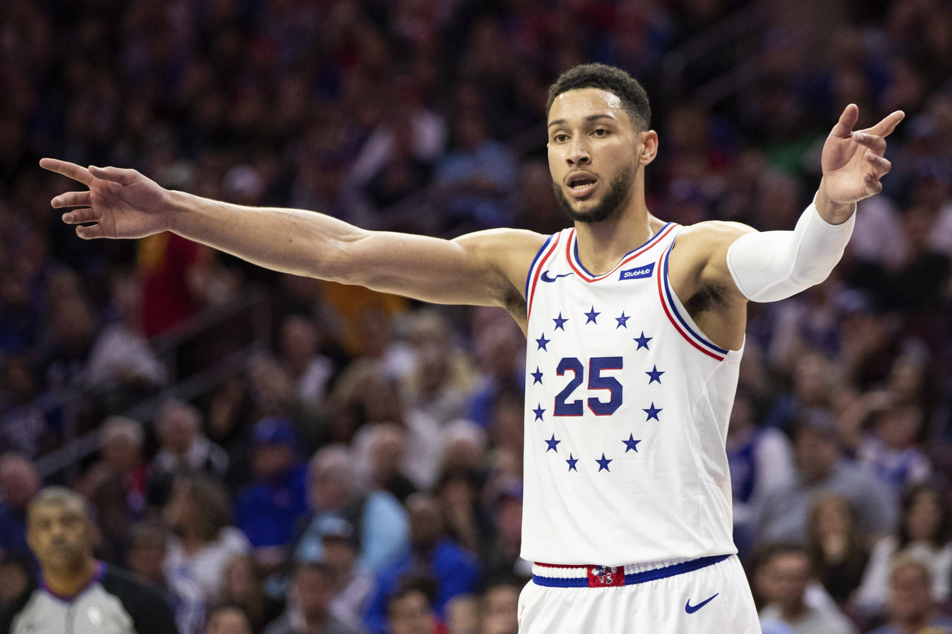 76ers 桌布 壁紙 — 一名身穿白色球衣、背號25號並帶有星星圖案的籃球運動員，在比賽中激動地做手勢，身後是模糊的人群。