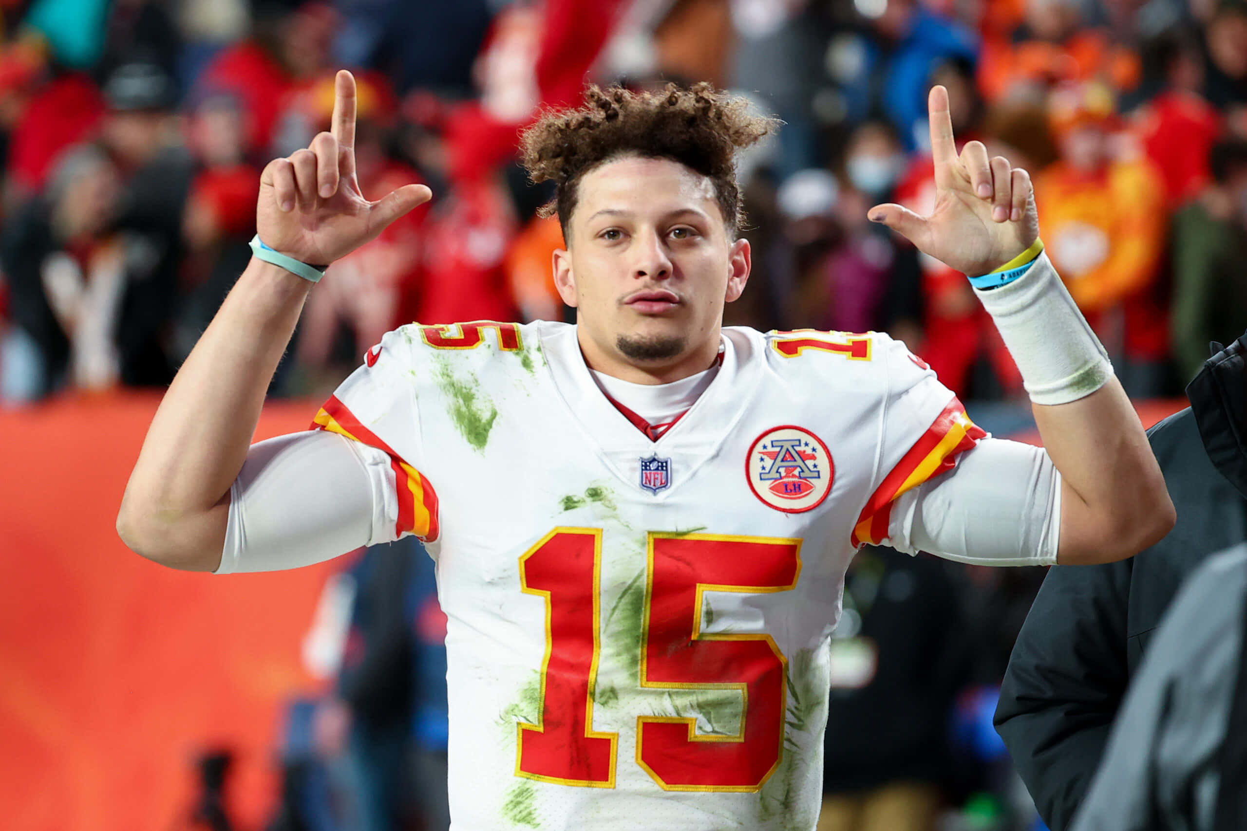 NFL 桌布 壁紙 — 一名身穿白色球衣、號碼15的美式足球四分衛在球場上高舉雙食指慶祝，背景有紅色和橙色的模糊球迷。