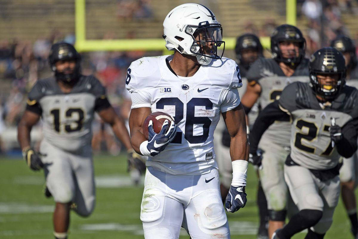 Saquon Barkley 桌布 壁紙 — 一名身穿白色球衣26號的足球員在陽光照耀的球場上帶球奔跑，對手在後面追趕。