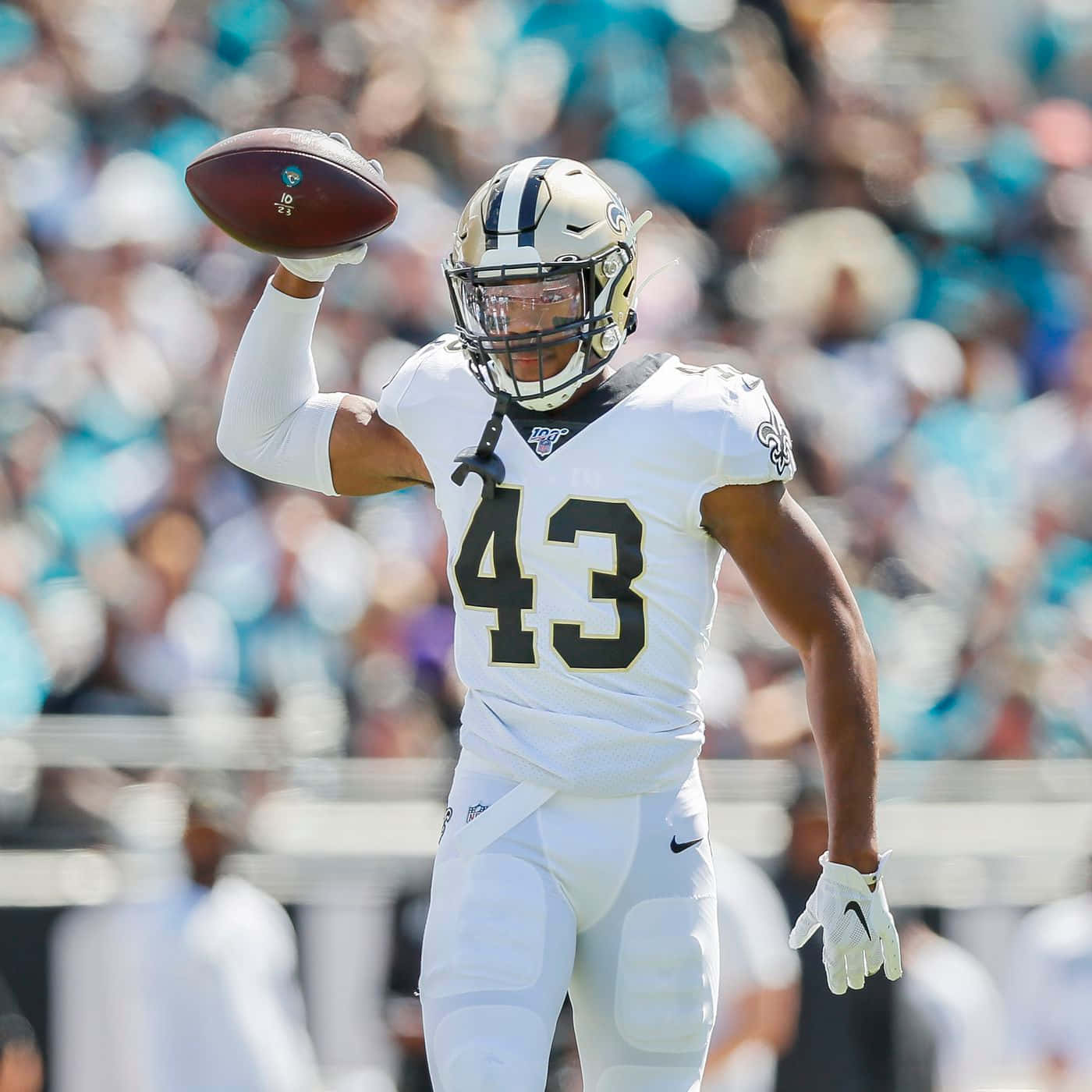 Marcus Williams 桌布 壁紙 — 一名身穿白色球衣43號的美式足球員在模糊的人群前高舉美式足球慶祝。