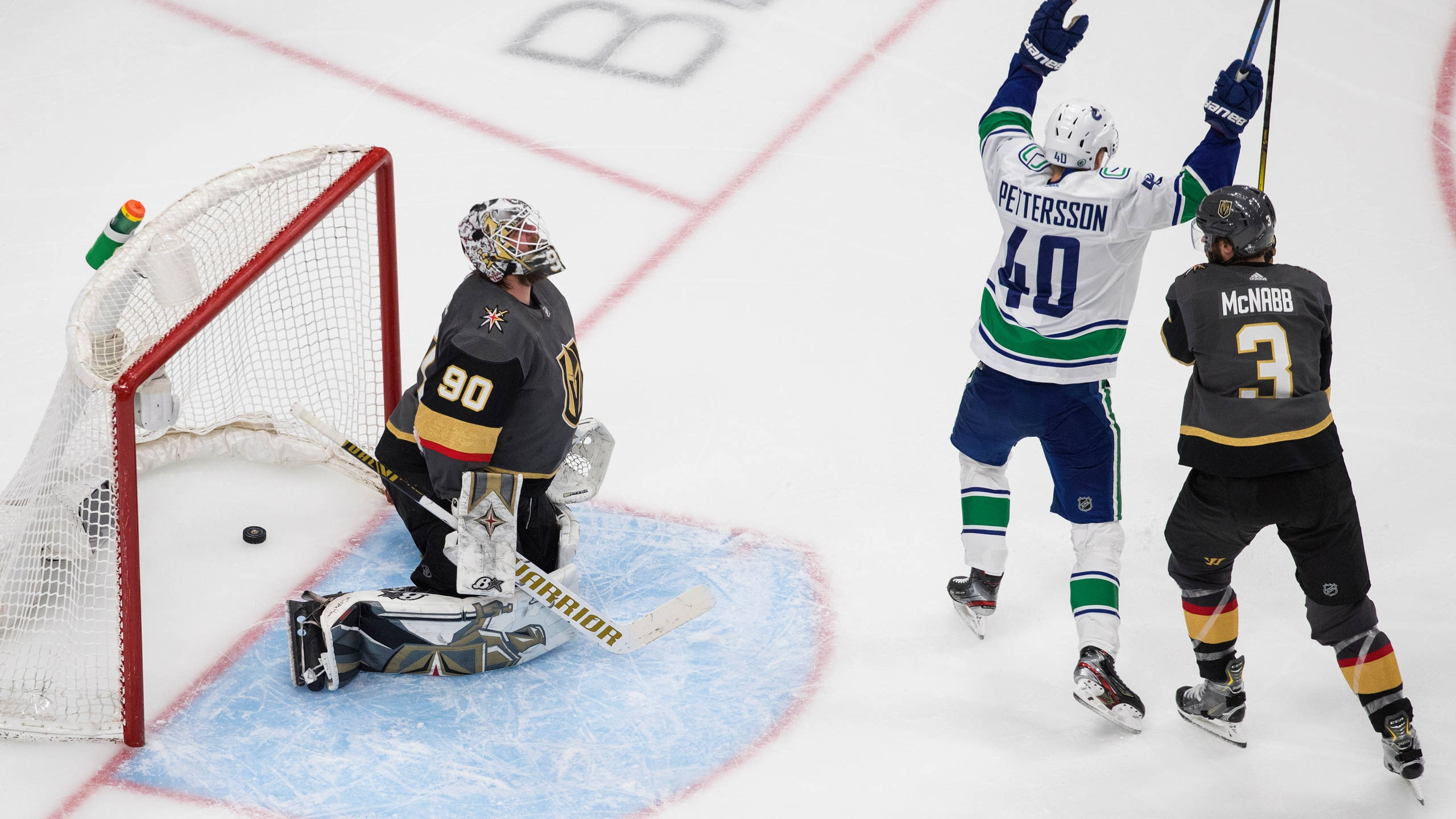 hockey 桌布 壁紙 — 一名身穿白色球衣的冰球運動員在冰上越過倒下的守門員得分後，勝利地跳躍。