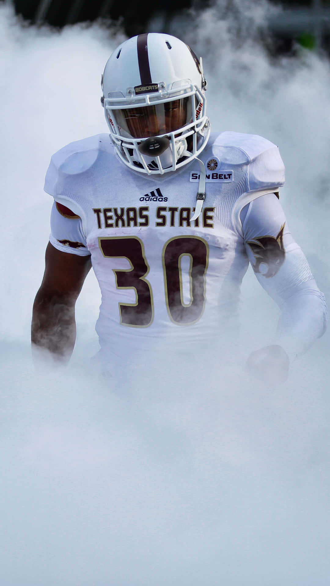 Texas Football 桌布 壁紙 — 一名身穿白色球衣的德州州立大學足球員從球場上的濃煙中出現。