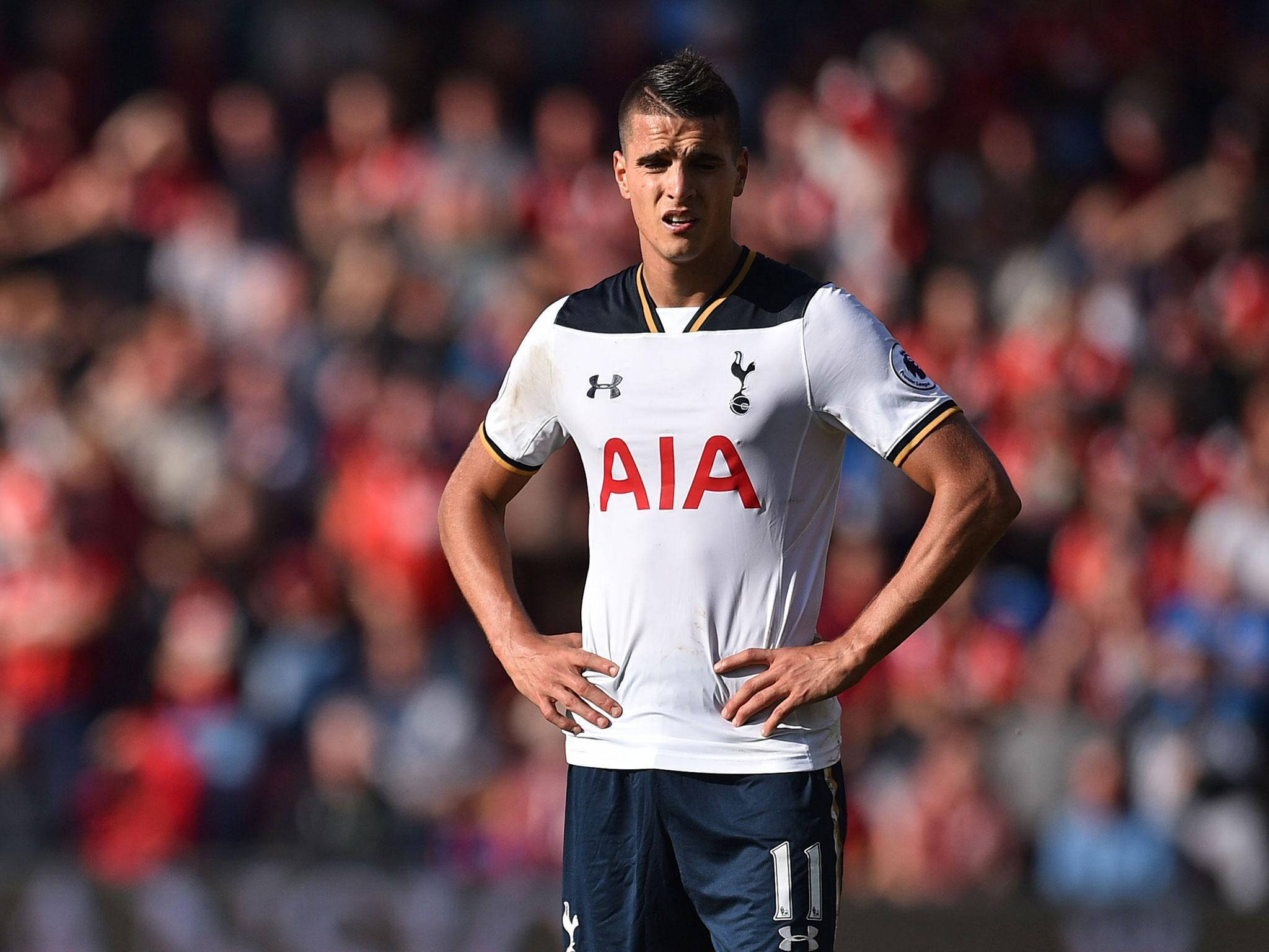 erik lamela 桌布 壁紙 — 一名身穿白色球衣的托特納姆熱刺足球員，雙手叉腰，背景是模糊的球場人群。