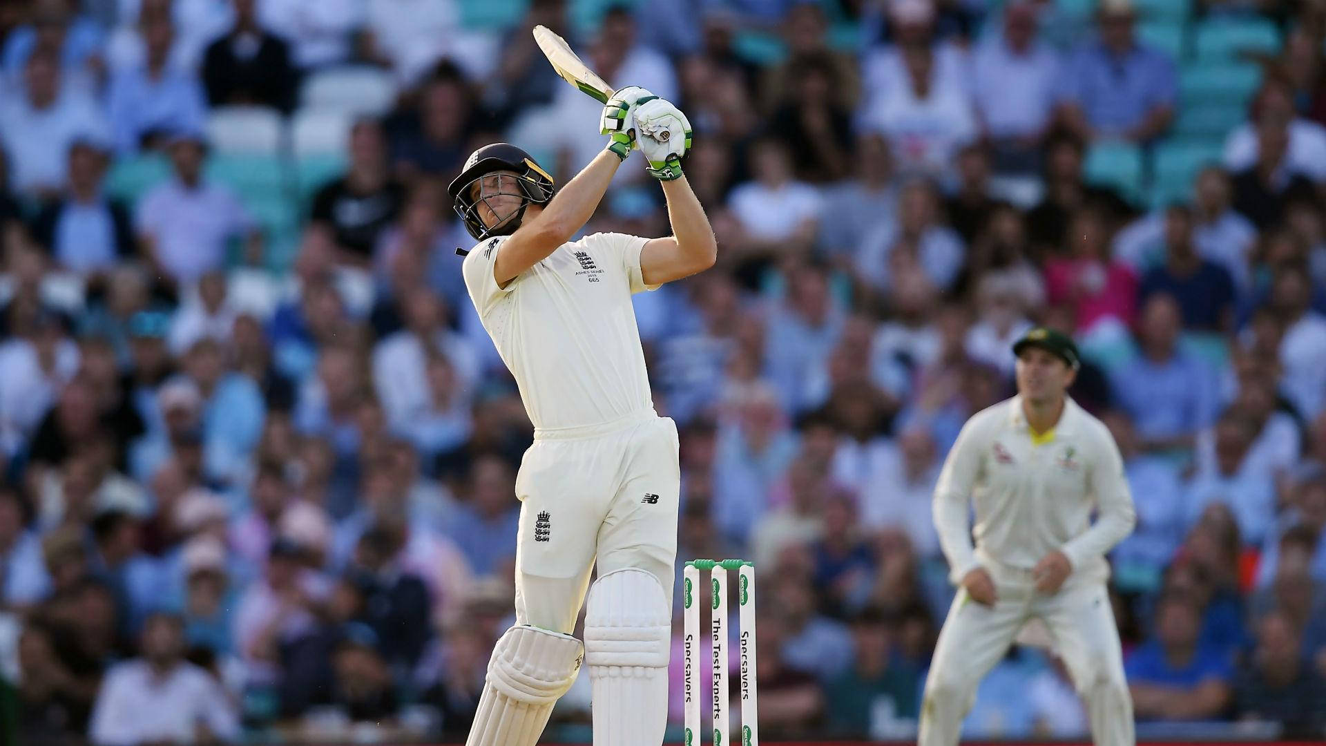jos buttler 桌布 壁紙 — 一名身穿白色球衣的板球擊球手高舉球棒慶祝勝利，背景觀眾歡呼。