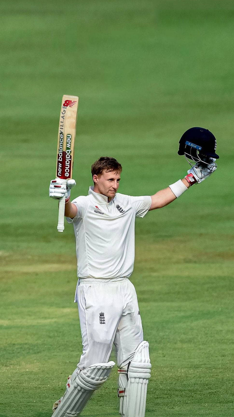 England Cricket 桌布 壁紙 — 一名身穿白色球衣的板球選手在翠綠的球場上高舉球棒和頭盔慶祝勝利。