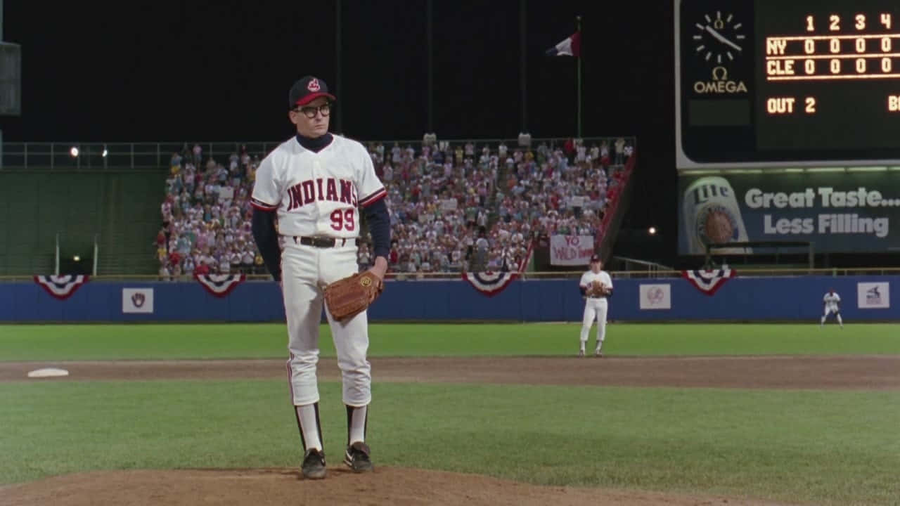 Major League Movie 桌布 壁紙 — 一名身穿白色球衣的棒球投手站在球場燈光下的投手丘上，背景是座無虛席的人群。