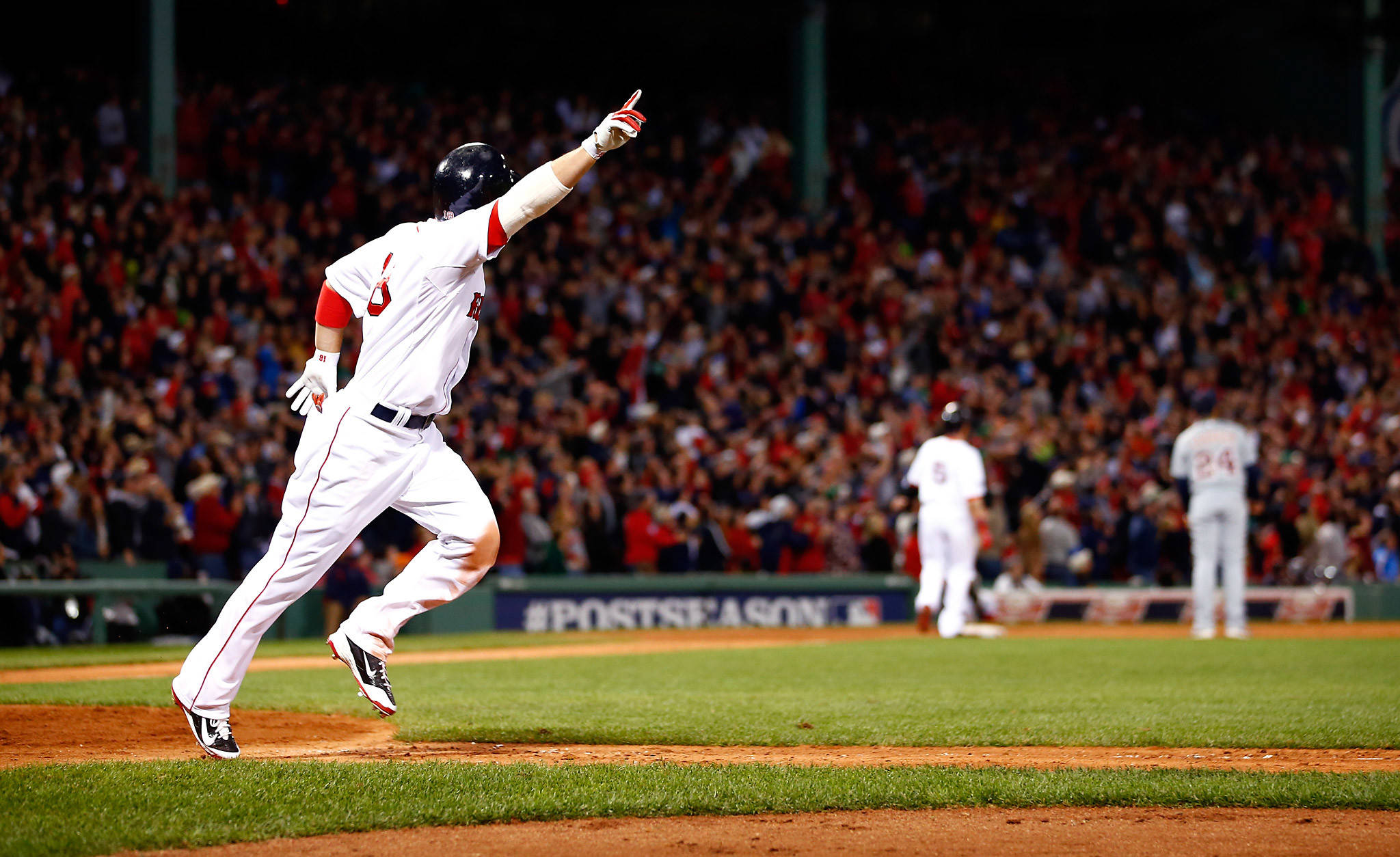 Red Sox 桌布 壁紙 — 一名身穿白色球衣的棒球運動員在燈光球場上高舉拳頭慶祝，背後人群歡呼。
