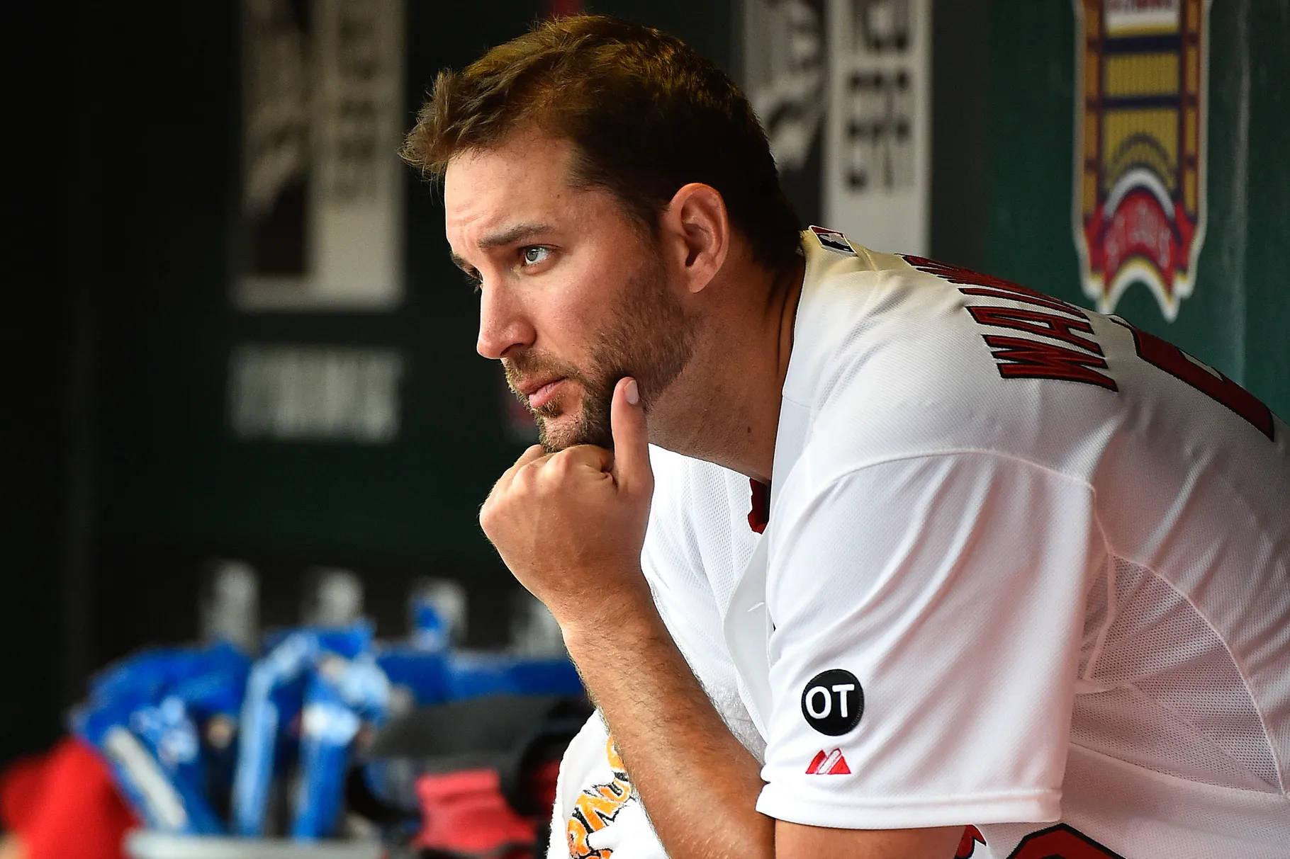 Adam Wainwright 桌布 壁紙 — 一名身穿白色球衣的棒球運動員在球員休息區用手指托著下巴，若有所思。