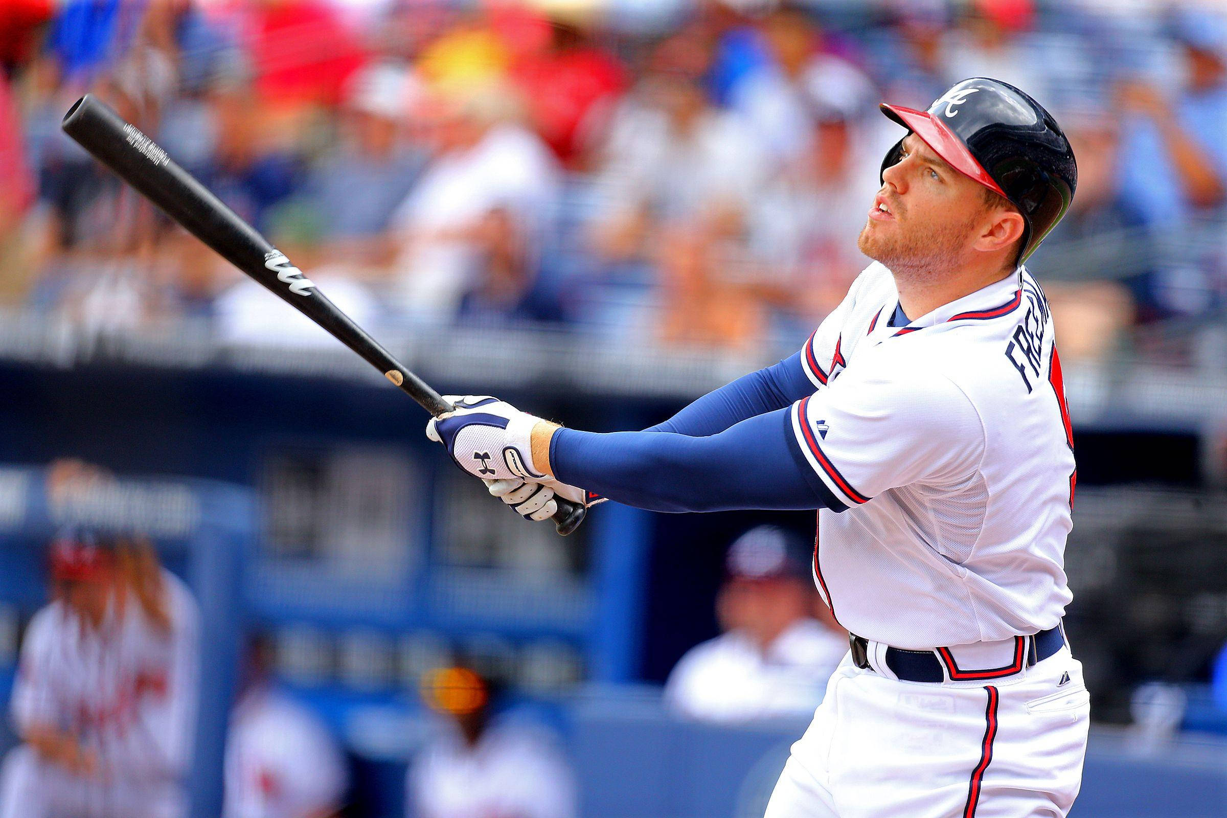 Freddie Freeman 桌布 壁紙 — 一名身穿白色球衣的棒球選手在日間比賽中專注地揮動黑色球棒，背景是模糊的觀眾。