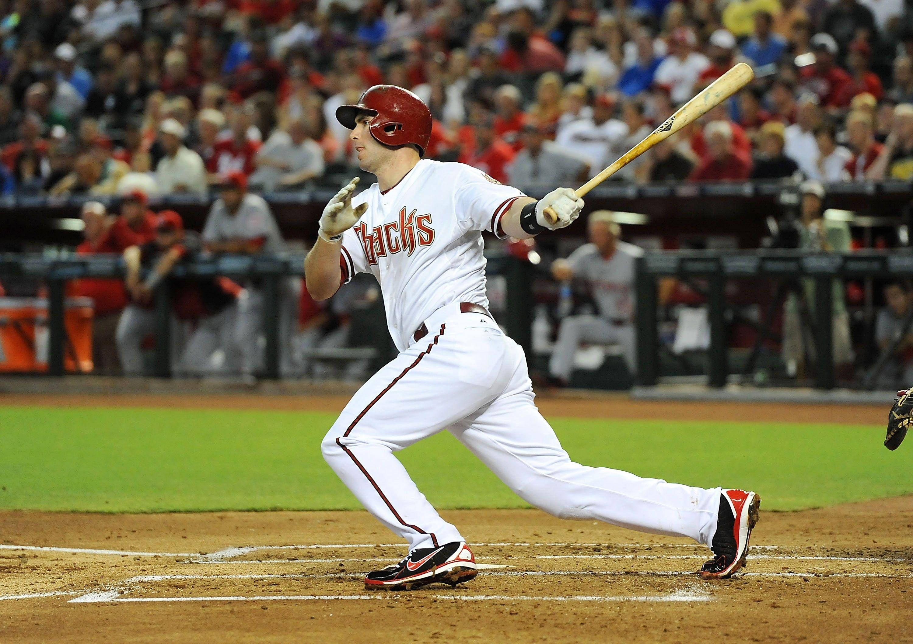Paul Goldschmidt 桌布 壁紙 — 一名身穿白色球衣的棒球選手在球場燈光下的夜間比賽中，專注地揮動球棒。