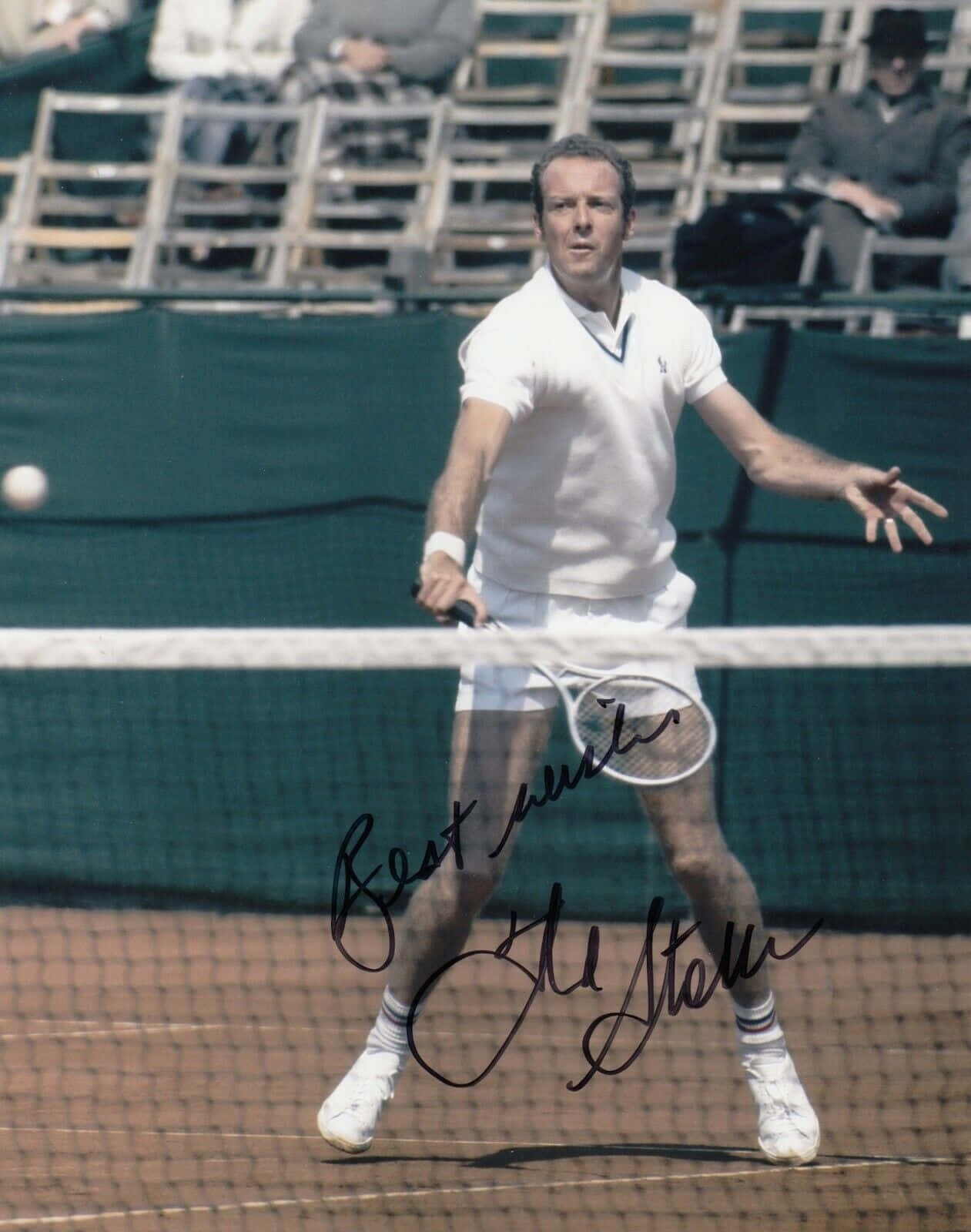 Tennis 桌布 壁紙 — 一名身穿白色球衣的男網球手向前撲出，在紅土球場上擊打一個低球，背景有觀眾。