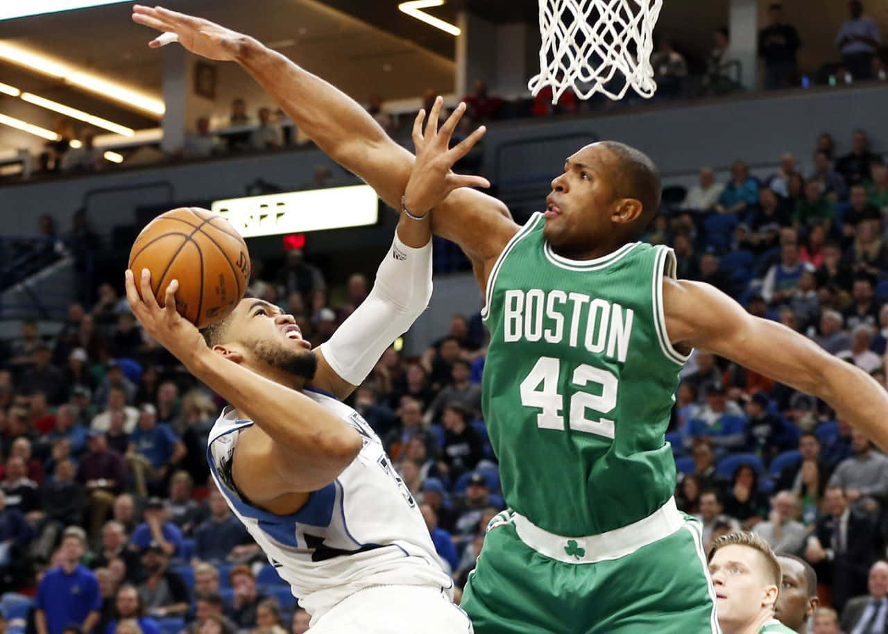 Al Horford 桌布 壁紙 — 一名身穿白色球衣的籃球運動員向籃框切入，同時被一名身穿綠色球衣的波士頓塞爾提克球員防守。
