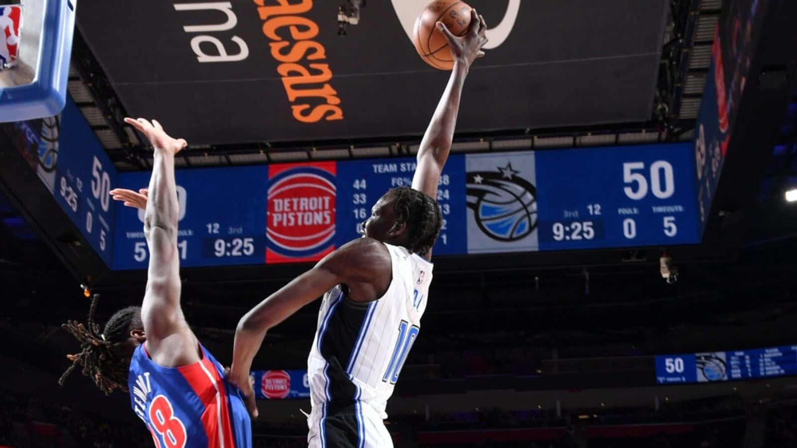 NBA 桌布 壁紙 — 一名身穿白色球衣的籃球運動員在場館燈光下激烈的比賽中高高躍起，越過藍色球衣的防守球員投籃。