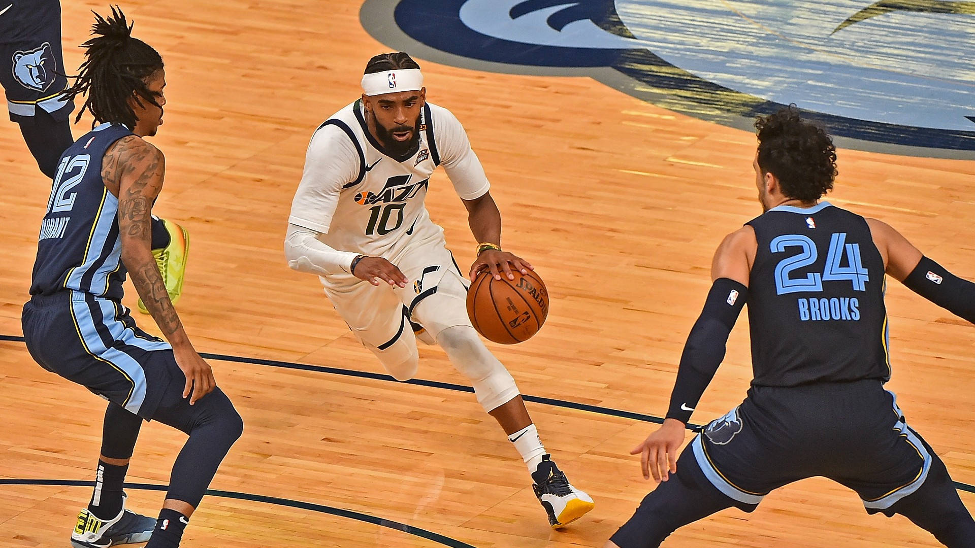 mike conley 桌布 壁紙 — 一名身穿白色球衣的籃球運動員在木地板上運球，同時被兩名對手防守。