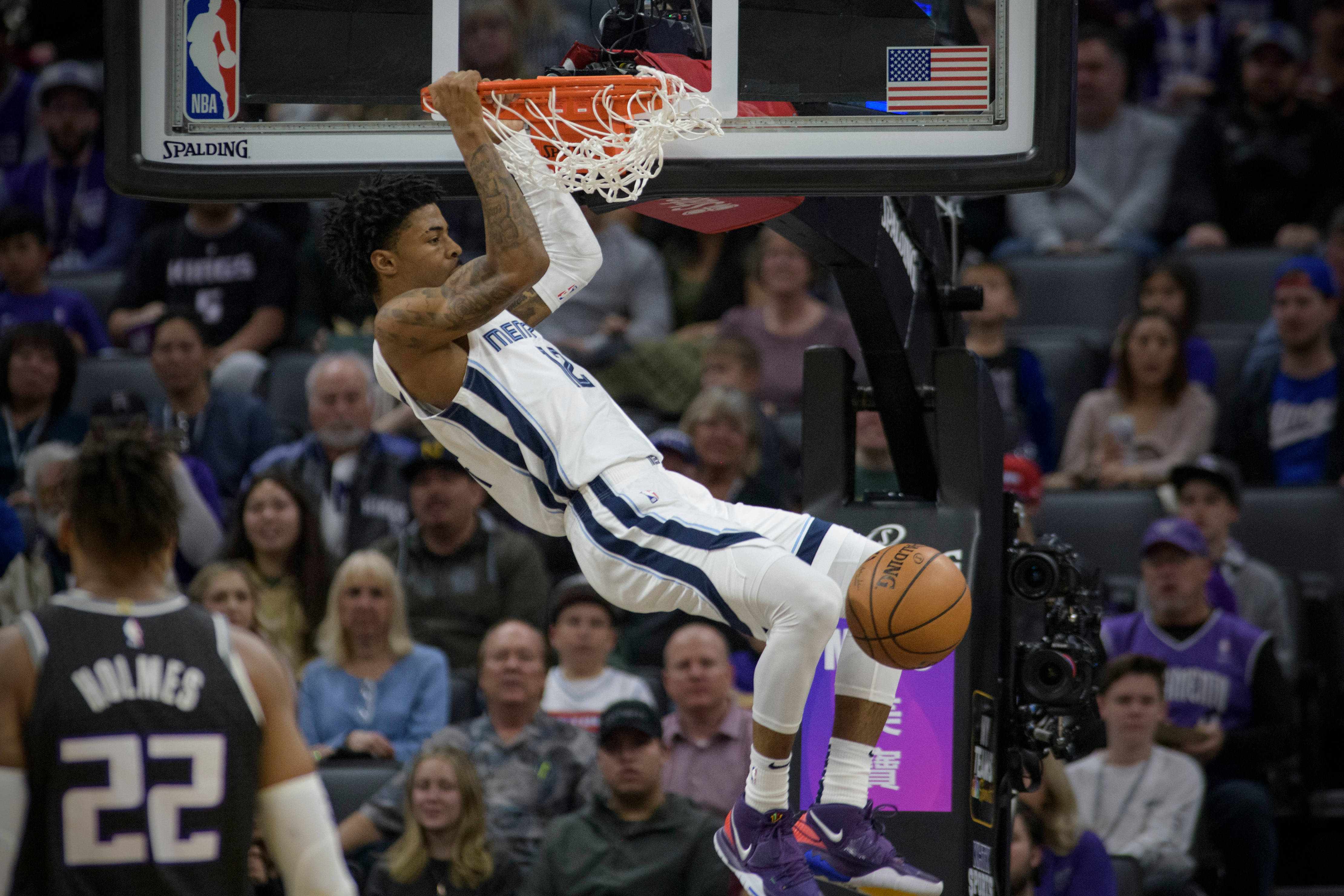 Ja Morant 灌籃 桌布 壁紙 — 一名身穿白色球衣的籃球運動員在比賽中單手灌籃，同時懸掛在籃框上。
