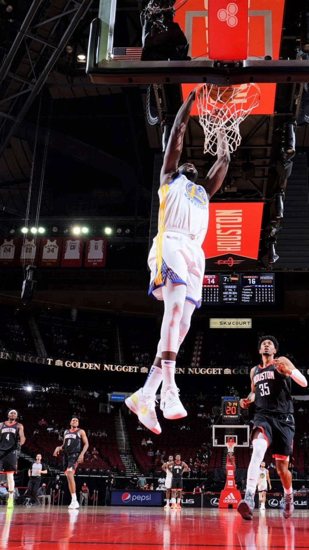 Draymond Green 桌布 壁紙 — 一名身穿白色球衣的籃球運動員在燈光明亮的球場中飛身灌籃。