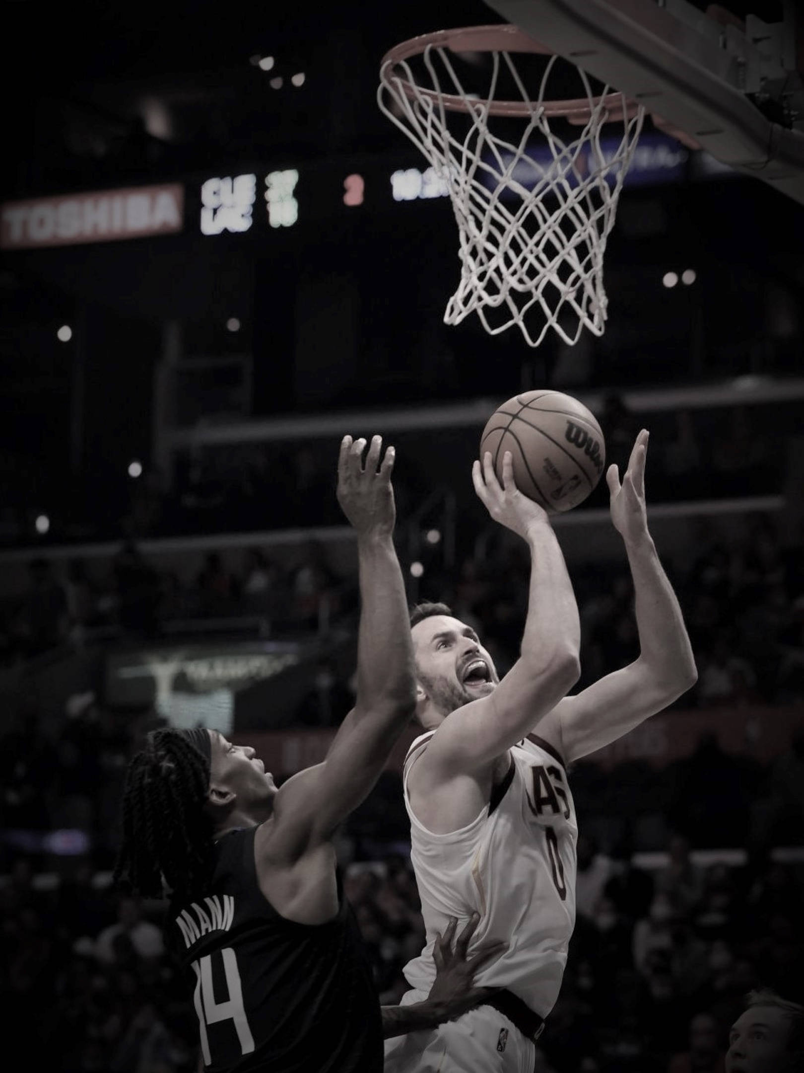 Kevin Love 桌布 壁紙 — 一名身穿白色球衣的籃球運動員跳向籃框，而一名身穿黑色球衣的防守球員在場館燈光下試圖封阻他的投籃。