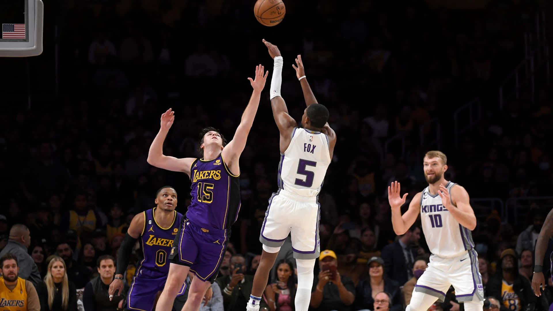 NBA 桌布 壁紙 — 一名身穿白色球衣的籃球運動員跳起投籃，而身穿紫色球衣的防守球員在明亮的場館燈光下干擾投籃。