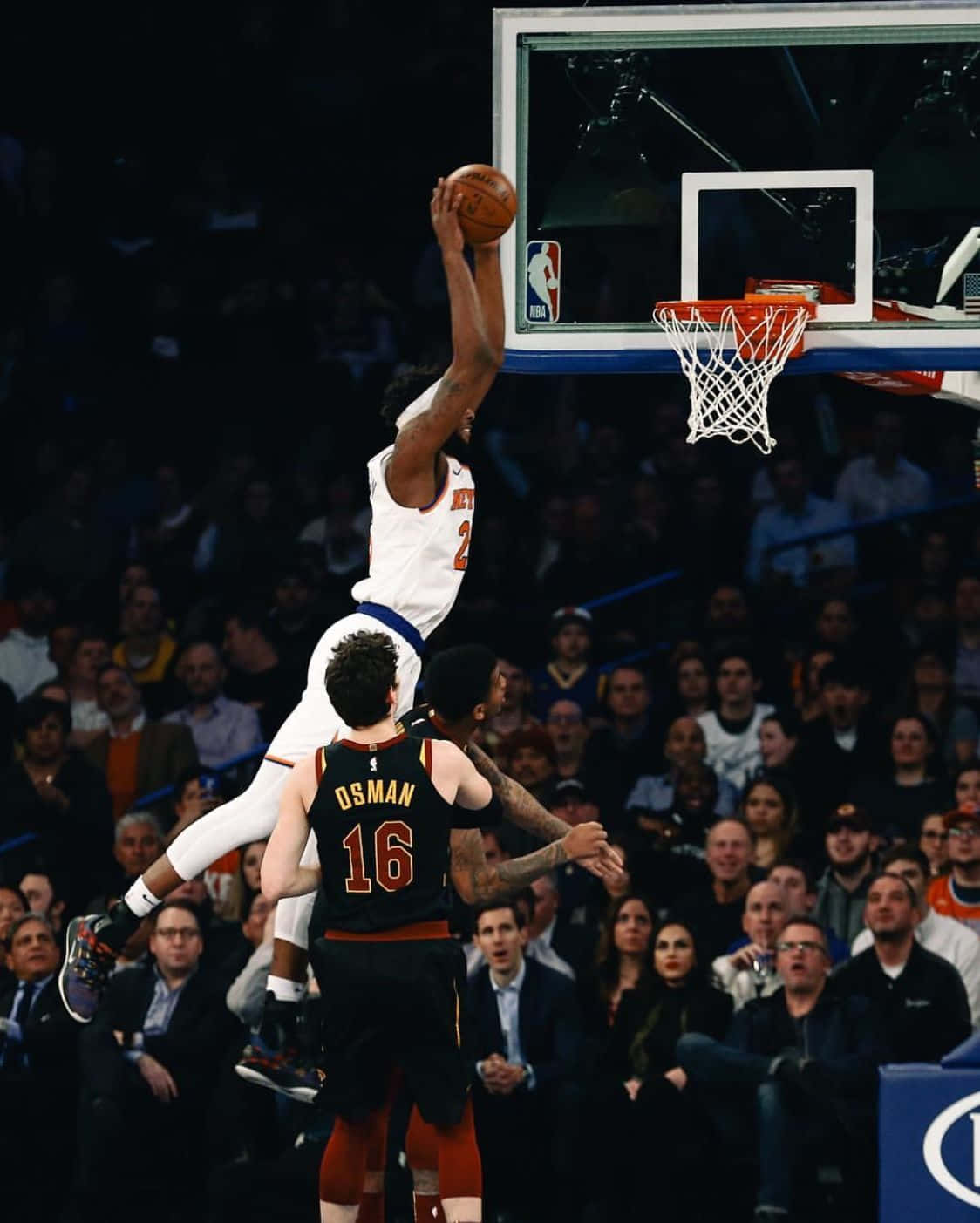 NBA 桌布 壁紙 — 一名身穿白色球衣的籃球運動員高高躍起準備灌籃，而一名身穿黑色球衣的防守球員在場館燈光下試圖封阻他。