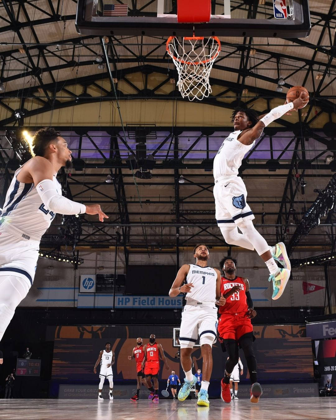 籃球運動員在半空中越過防守球員灌籃。 — Ja Morant 動圖 壁紙