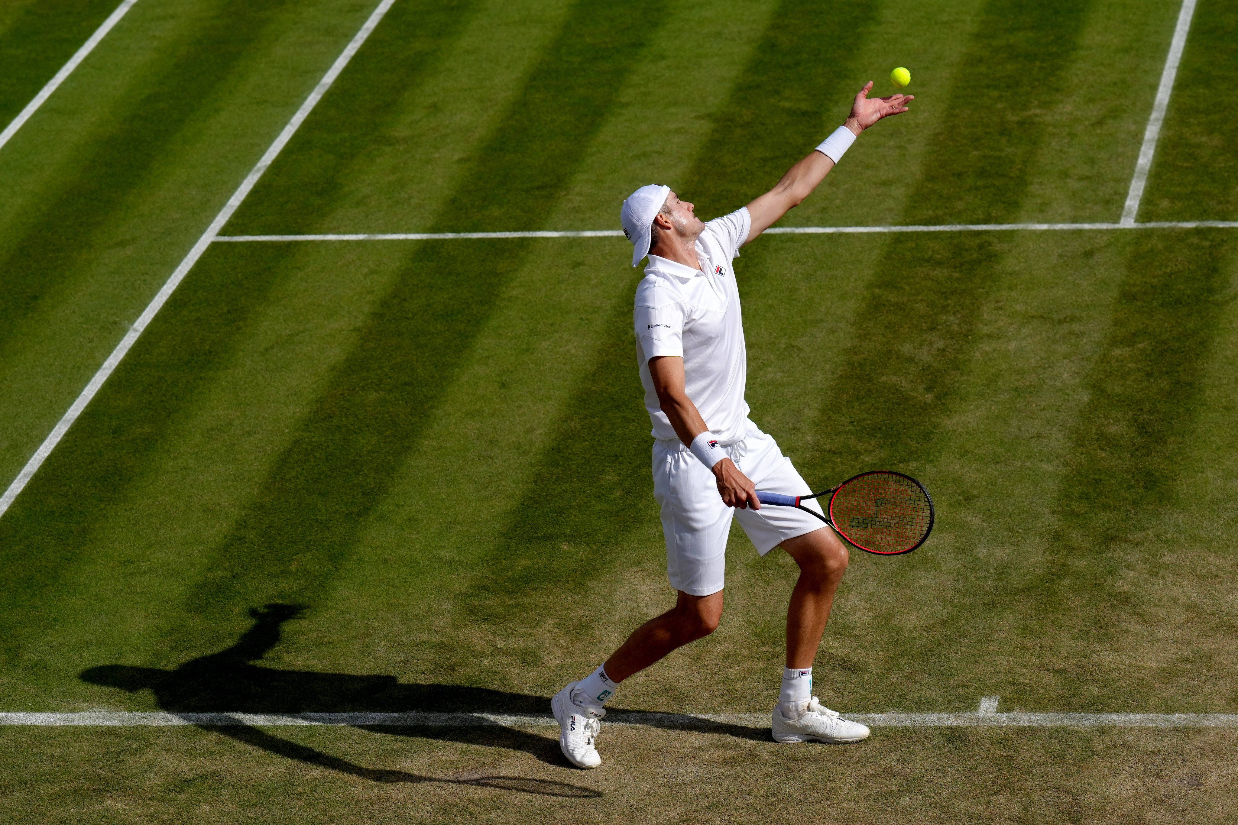 Tennis 桌布 壁紙 — 一名身穿白色球衣的網球選手在陽光明媚的草地場上將黃色球拋向空中，投下長長的影子。