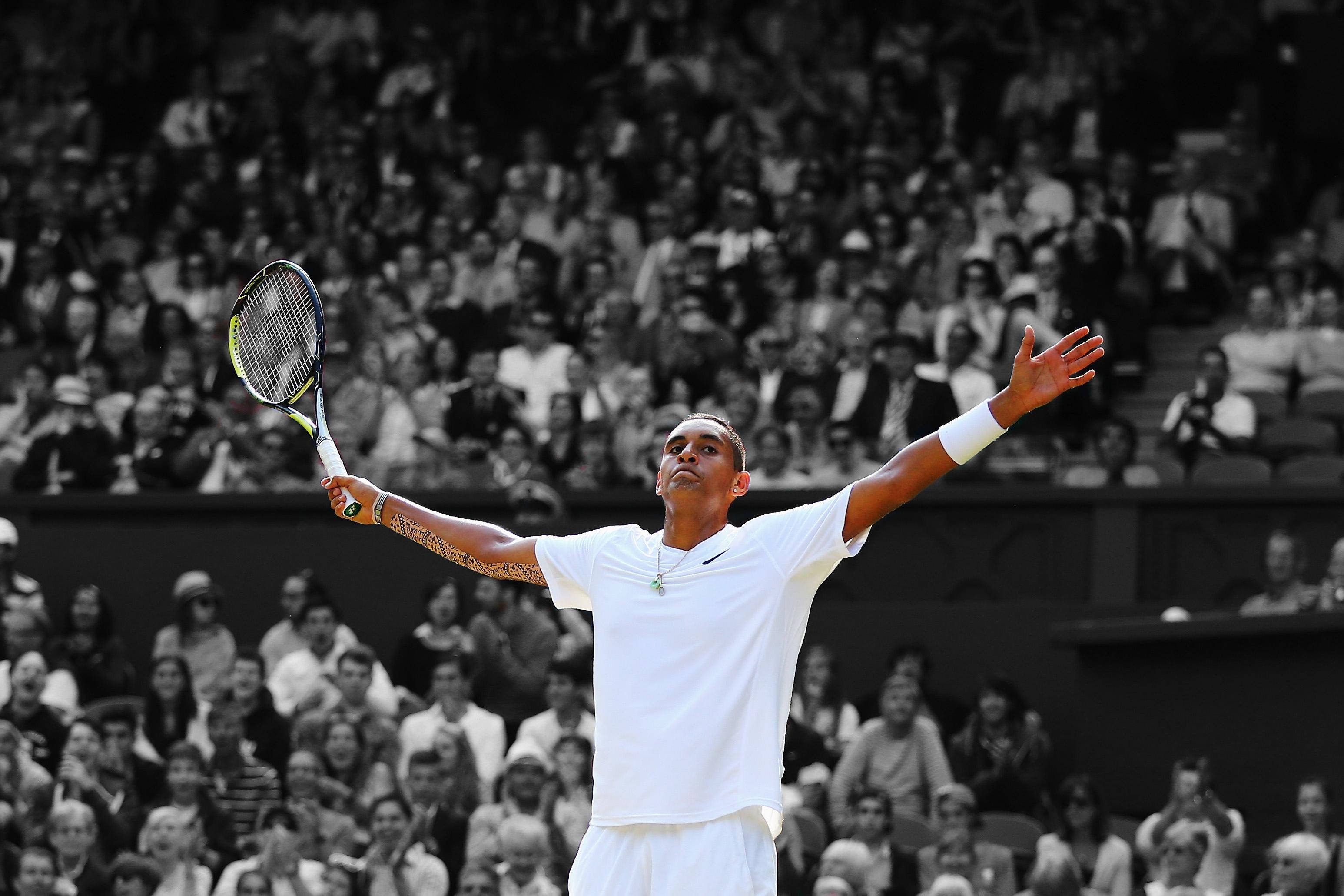 Kyrgios 桌布 壁紙 — 一名身穿白色球衣的網球選手高舉球拍，在歡呼的人群面前舉起雙臂慶祝勝利。