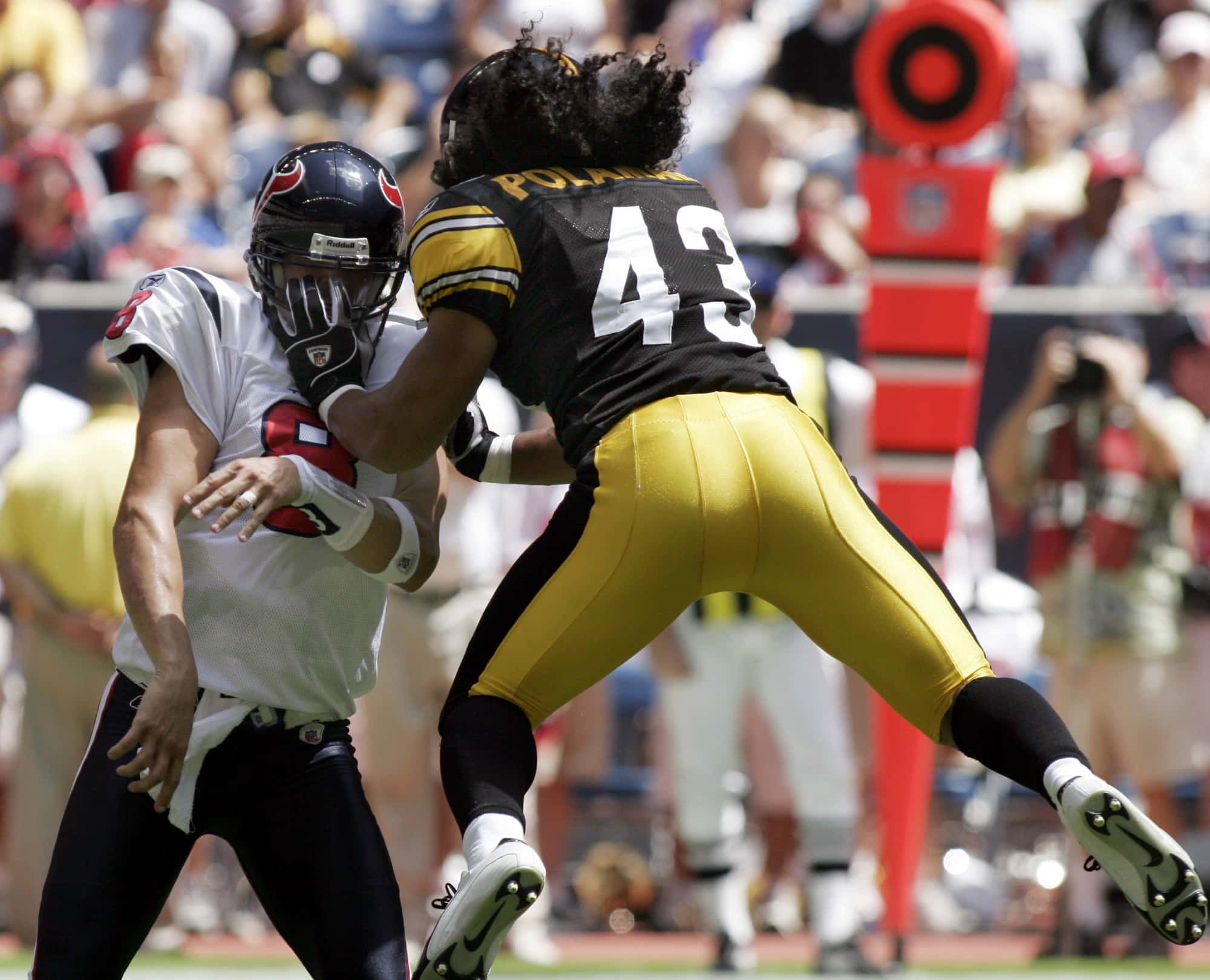 Troy Polamalu 桌布 壁紙 — 一名身穿白色球衣的美式足球四分衛在日間比賽中被身穿黑金色球衣的42號球員擒抱。