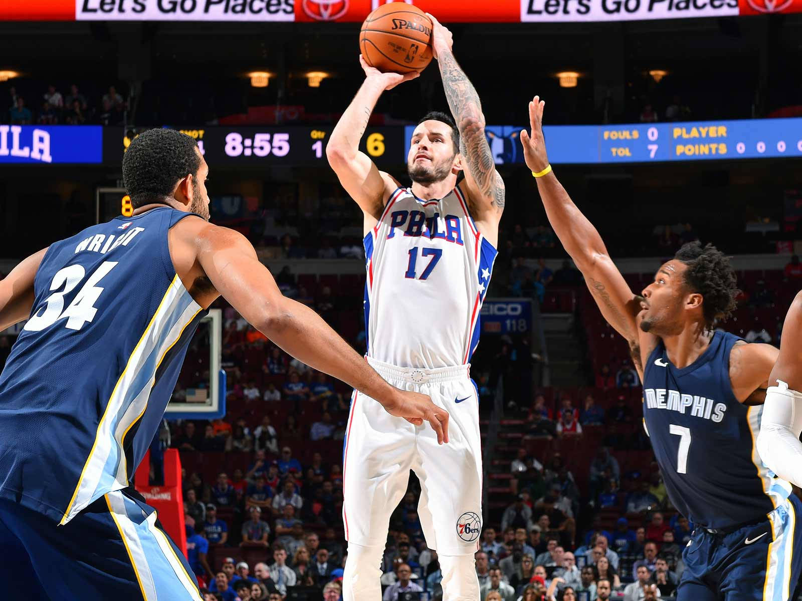 Jj Redick 桌布 壁紙 — 一名身穿白色球衣的費城76人球員正在投籃，兩名曼菲斯灰熊防守球員在場館燈光下干擾投籃。