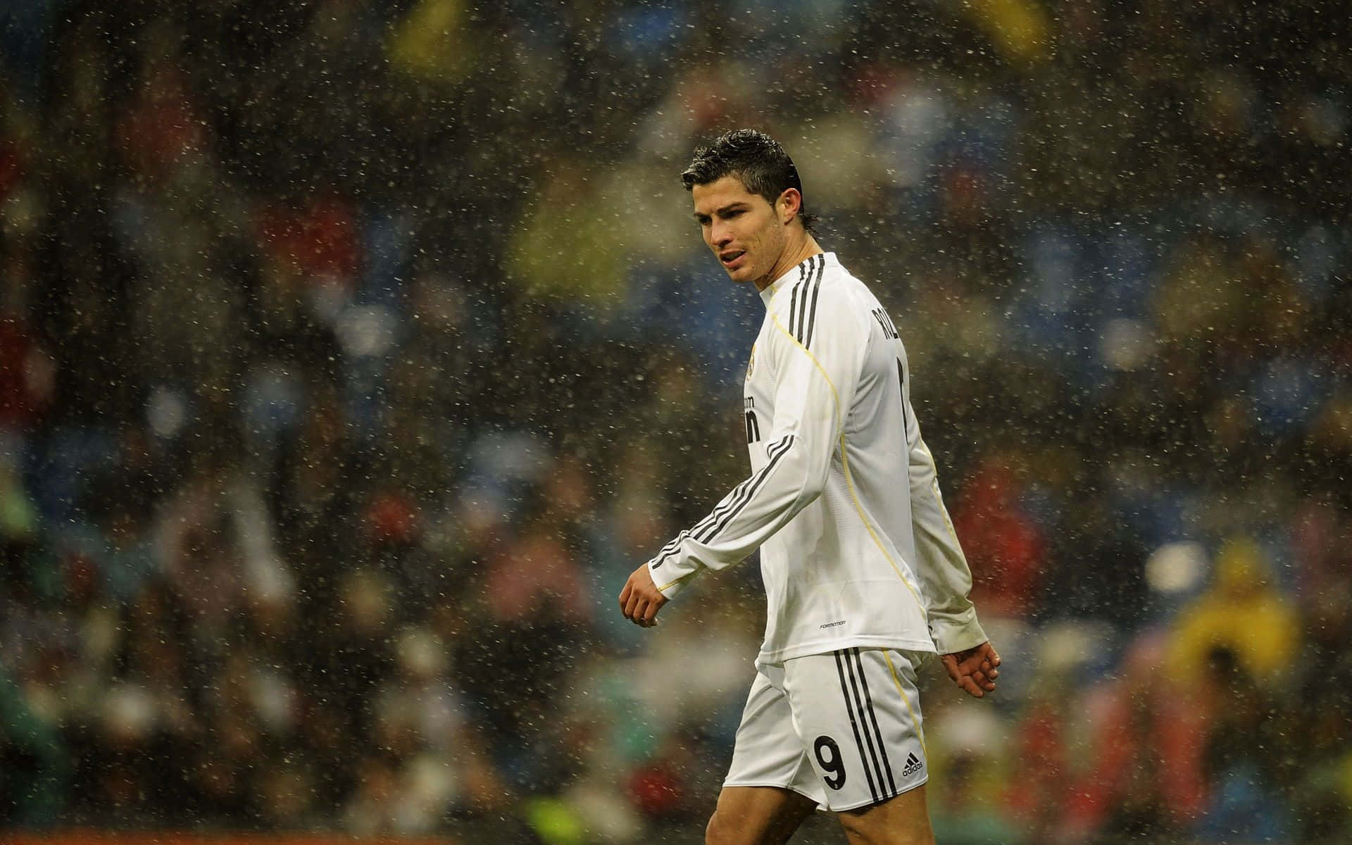 Ronaldo 桌布 壁紙 — 一名身穿白色球衣的足球員在滂沱大雨中走過球場，背景是模糊的觀眾。